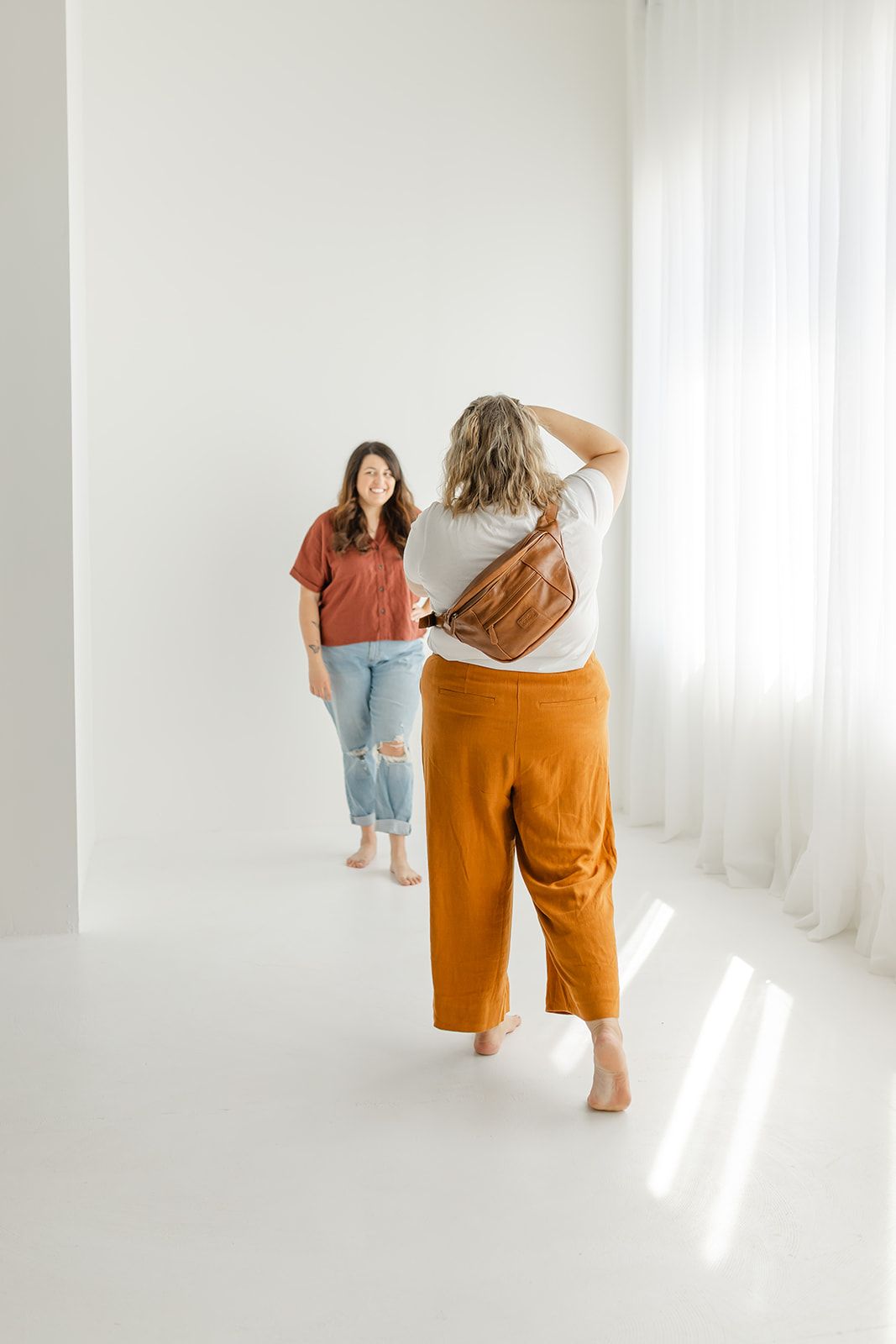 Two women standing in a bright, white room.