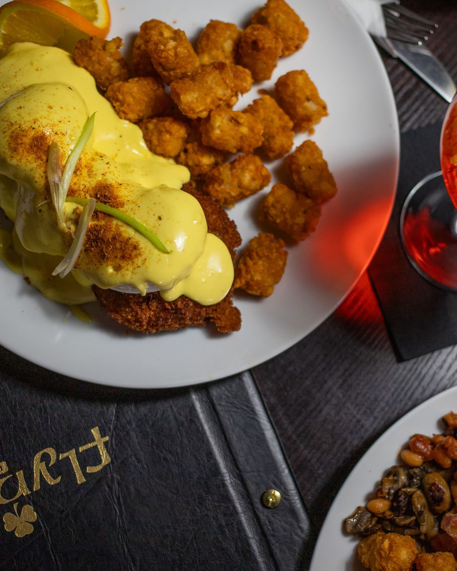 A plate of fried chicken and waffles, accompanied by a glass of orange juice, on a wooden table.