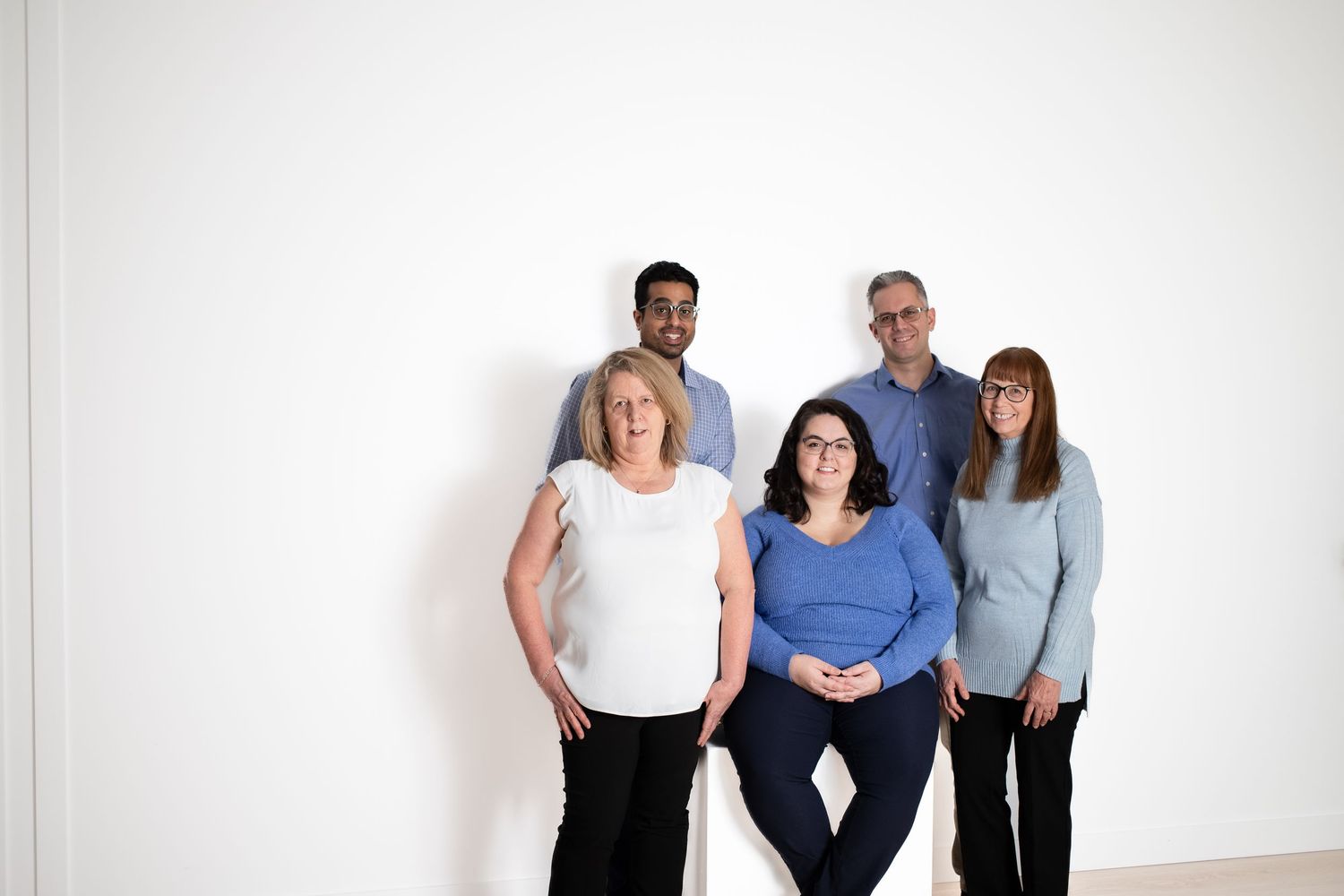 A group portrait of five people standing against a white background.
