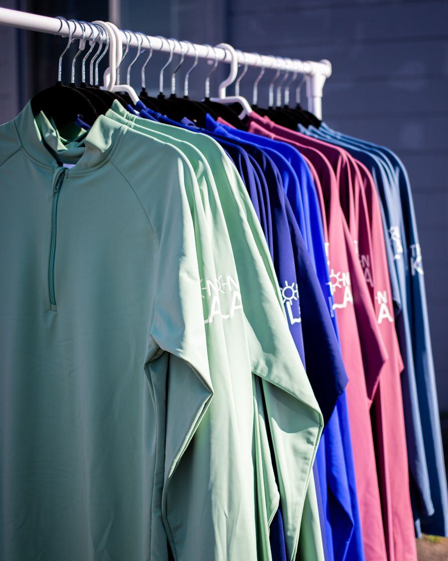 Rack of colorful shirts and tops hanging on a clothing rack.