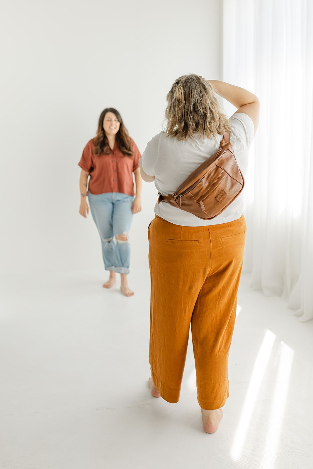 A woman poses for a photograph, surrounded by photography equipment in a bright, white studio.