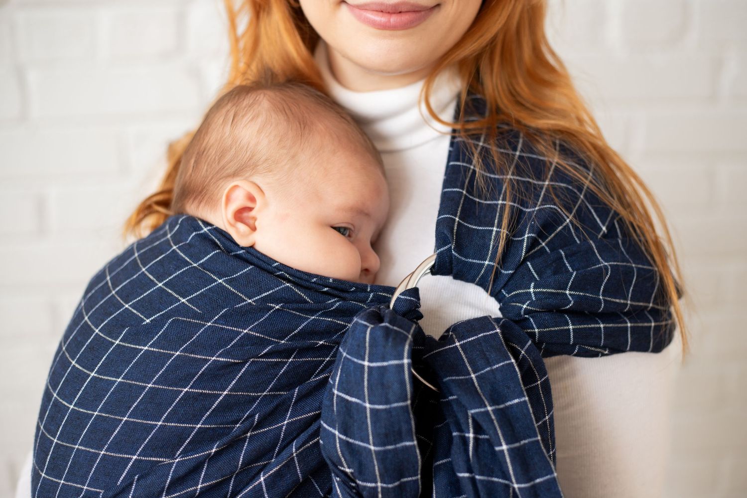 A woman with long red hair wearing a plaid shirt and jeans.