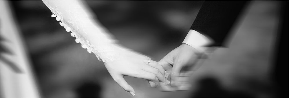 A tender black and white close-up of a couple’s hands gently intertwined, the bride’s lace sleeve and diamond ring visible in NYC
