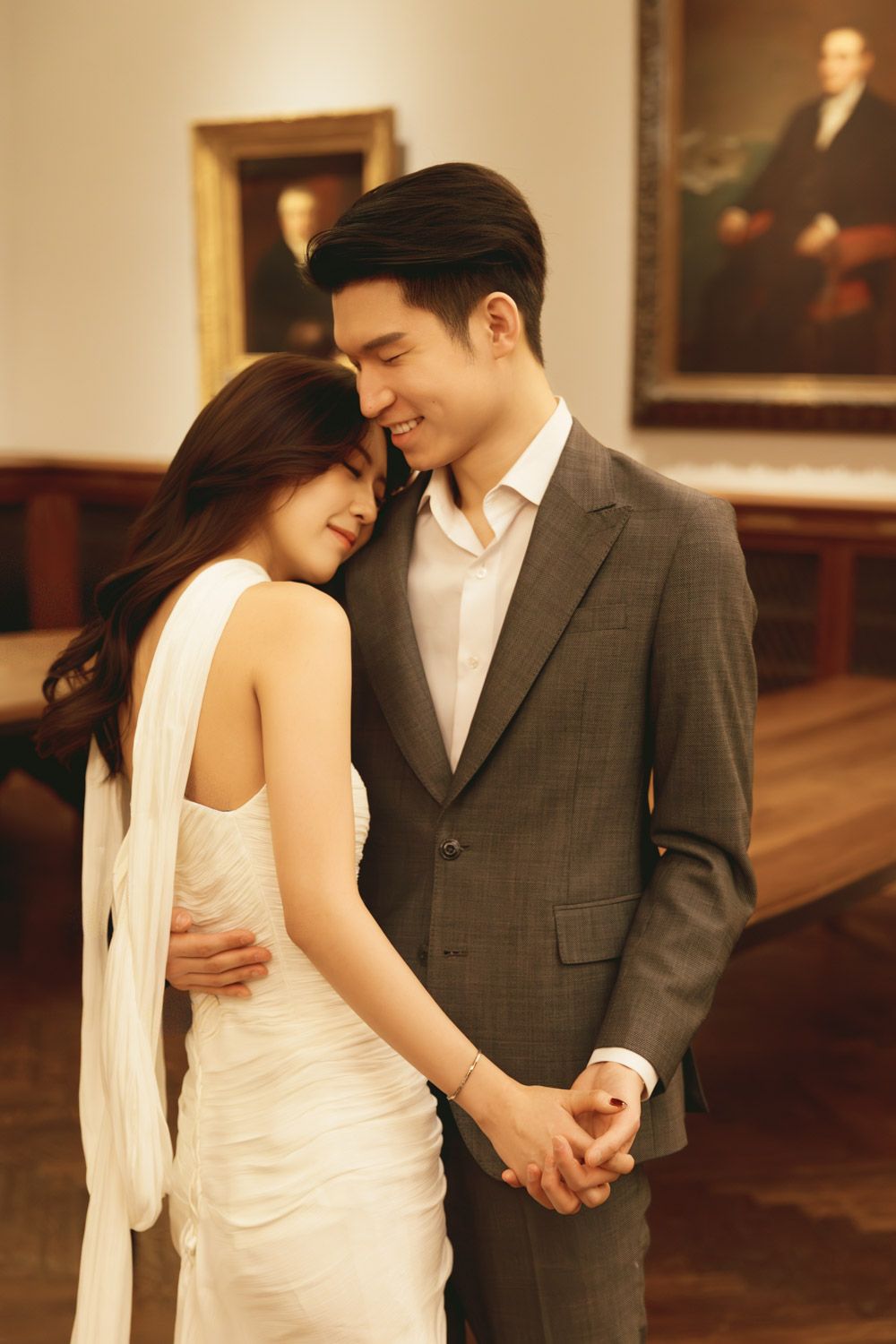 An asian couple shares an intimate and timeless moment with the bride resting her head on her partner’s shoulder in New York Public Library.