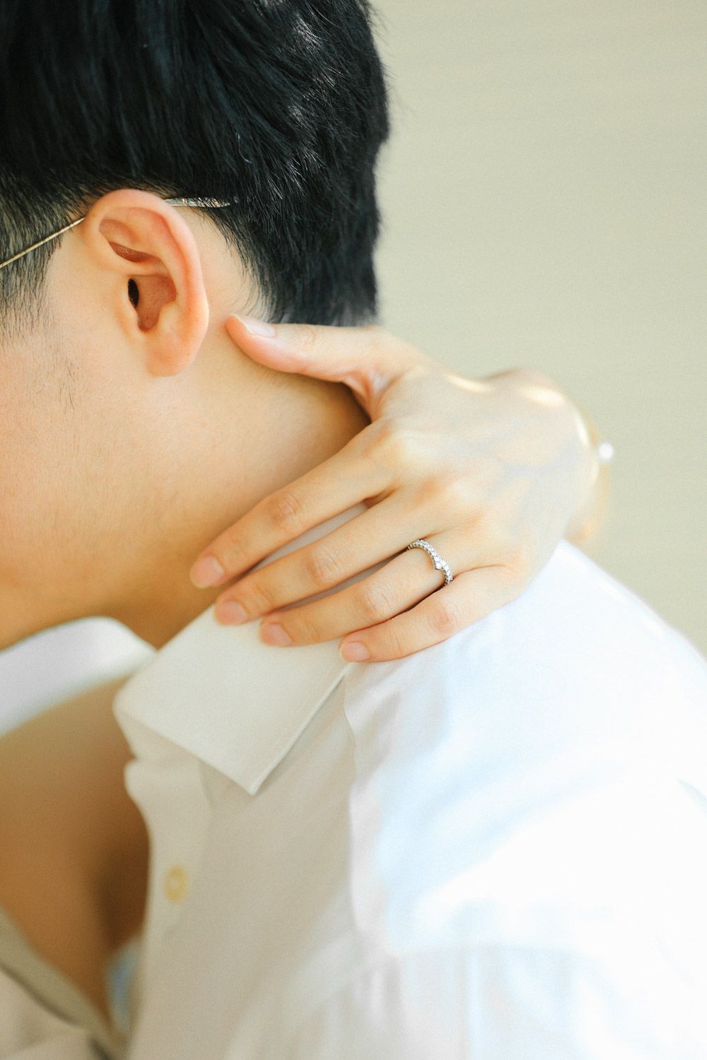 A woman gently rests her hand with diamond engagement ring on her partner’s neck during an intimate timeless New York engagement session.