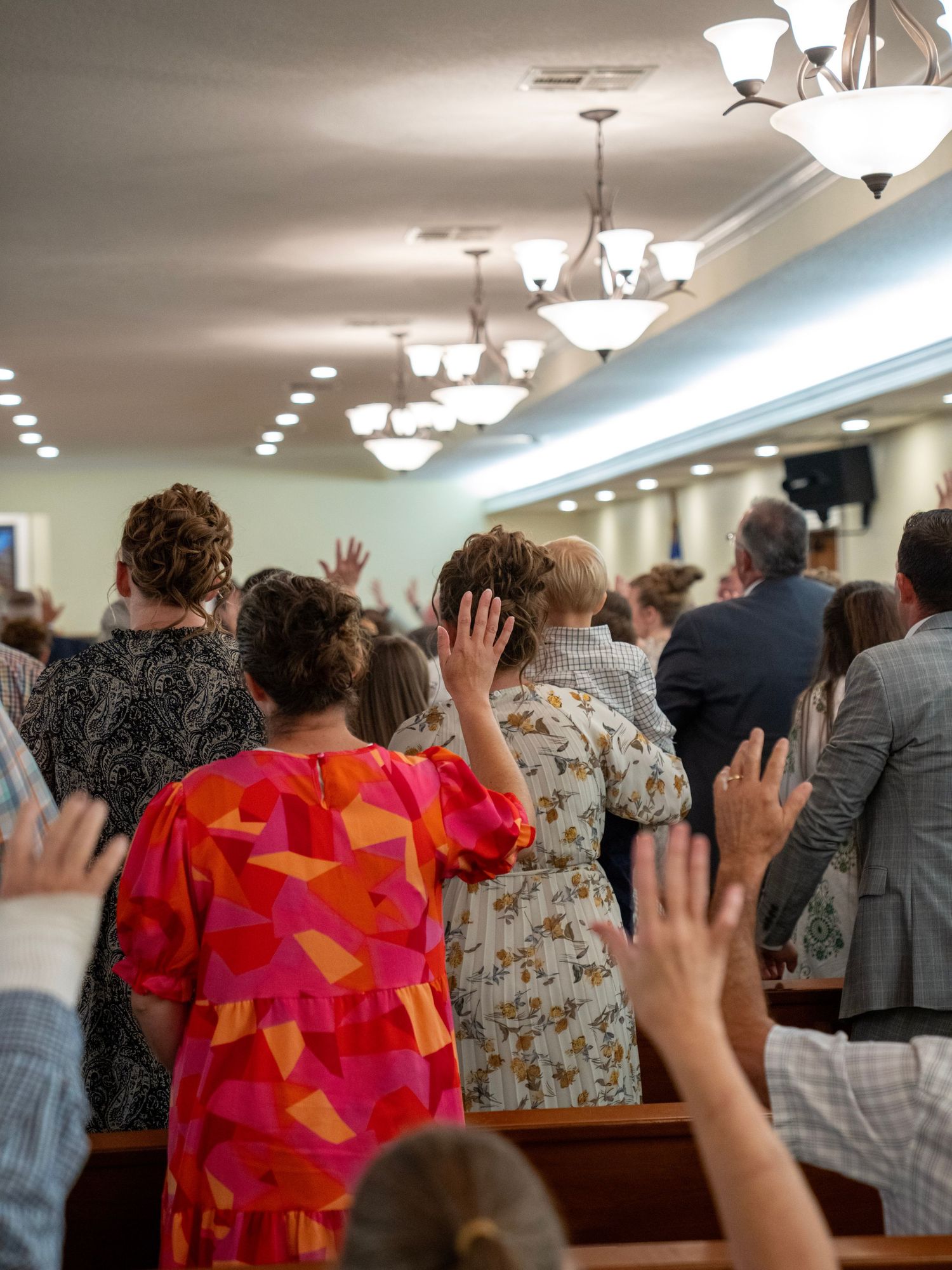 Congregation raising hands in worship during a packed church service.