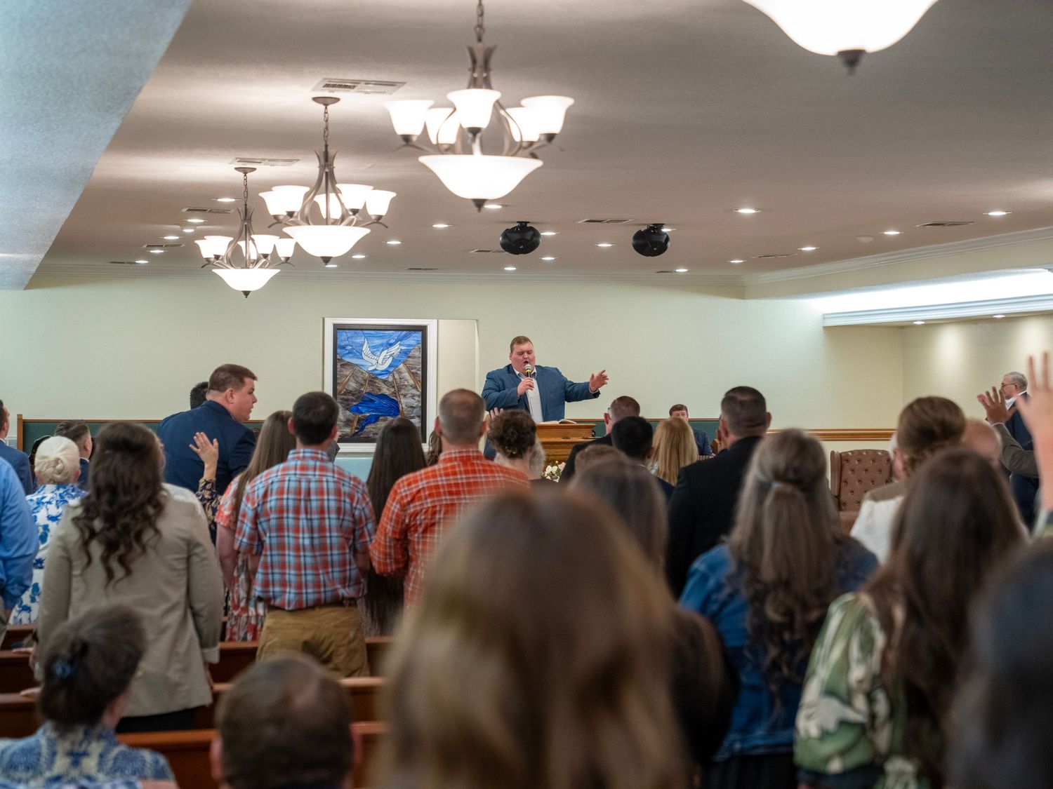 Preacher addressing a standing congregation during a lively church worship service.