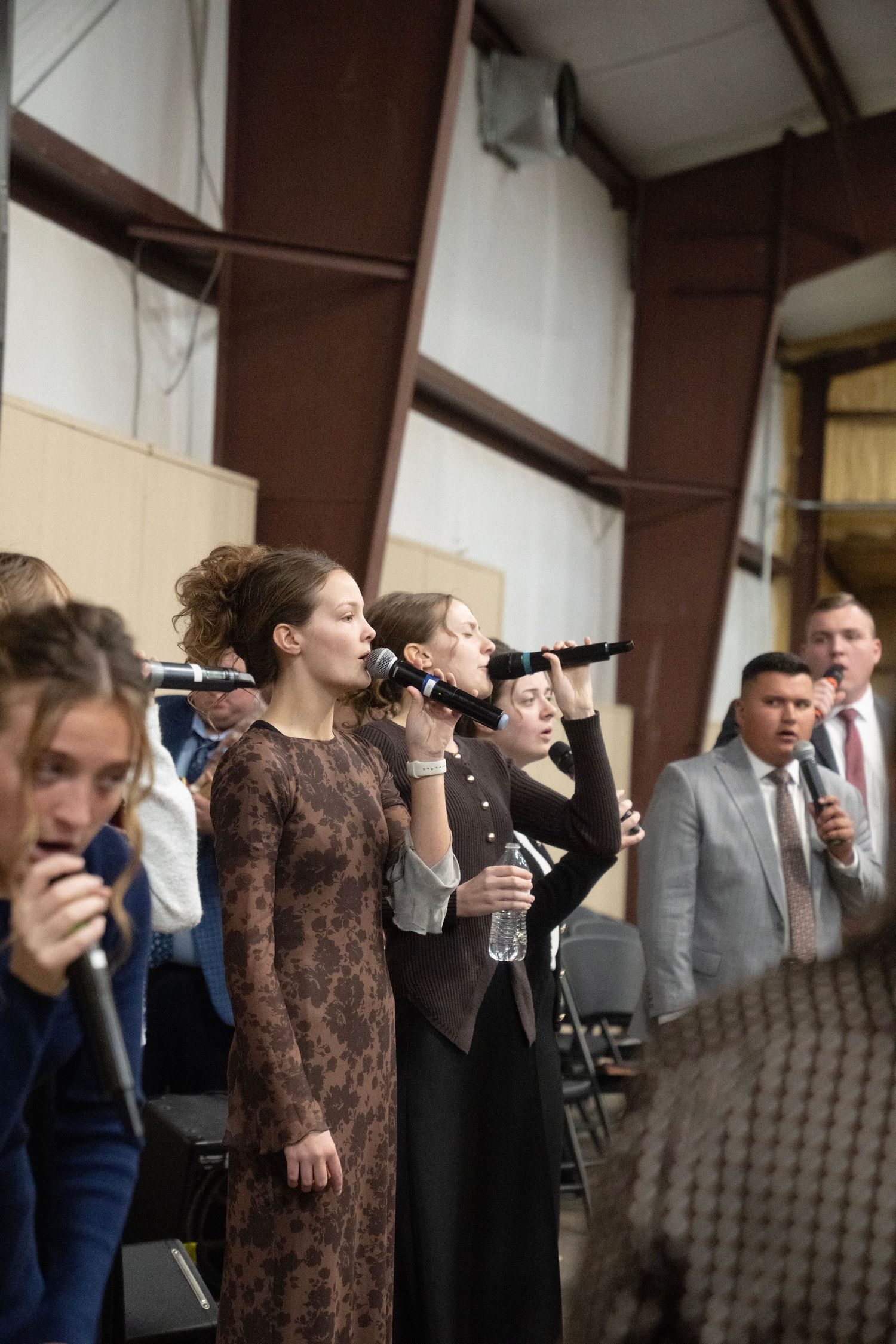 Choir performers singing into microphones at a church worship service.
