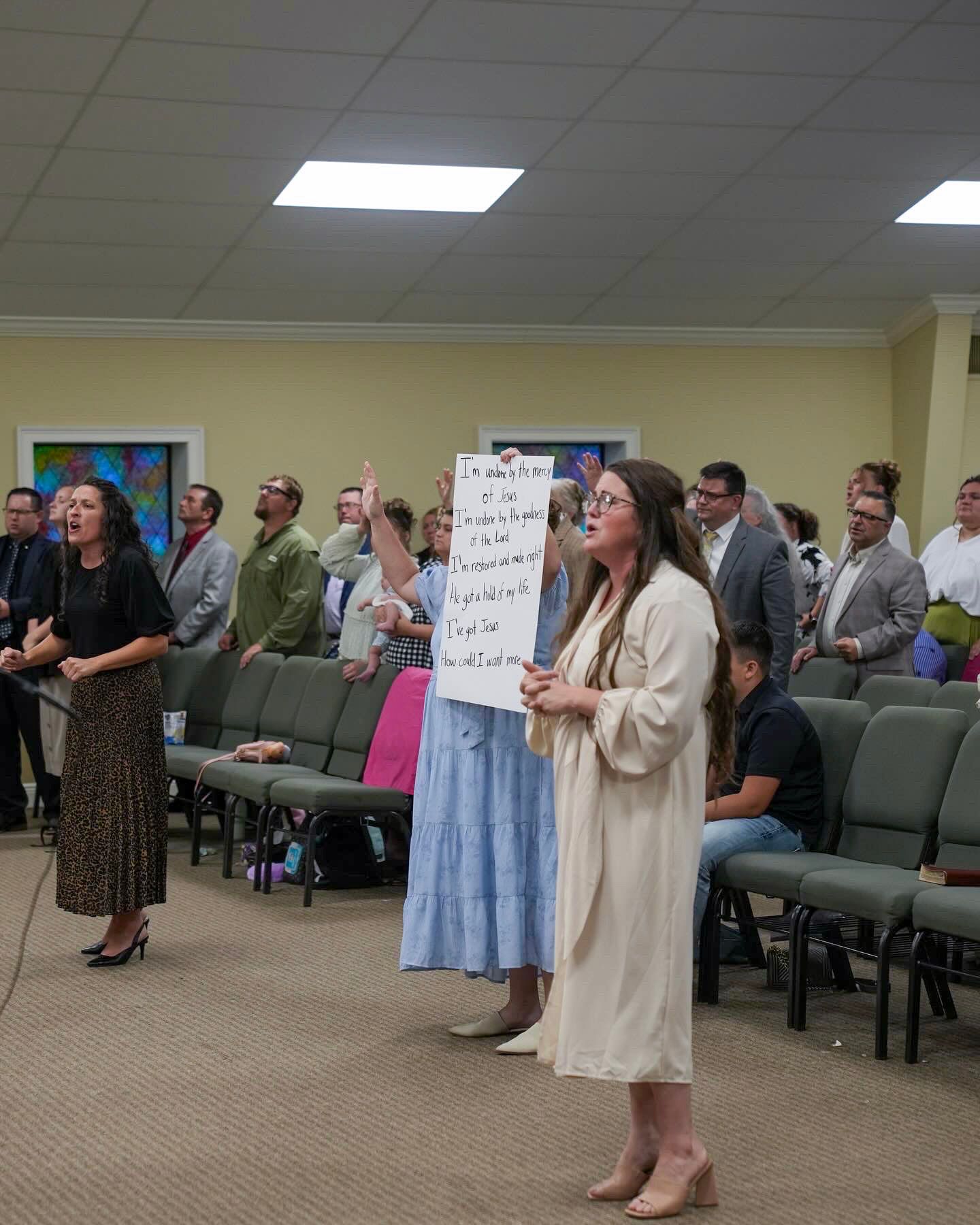 Congregation singing and worshipping with lyric sign during lively church service.