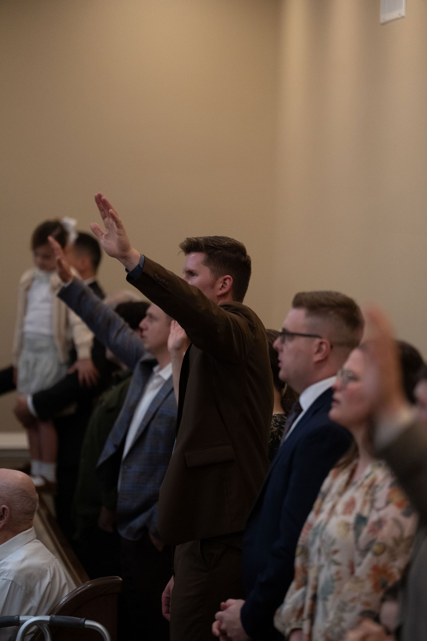 Congregation members raising hands in worship during a church service.