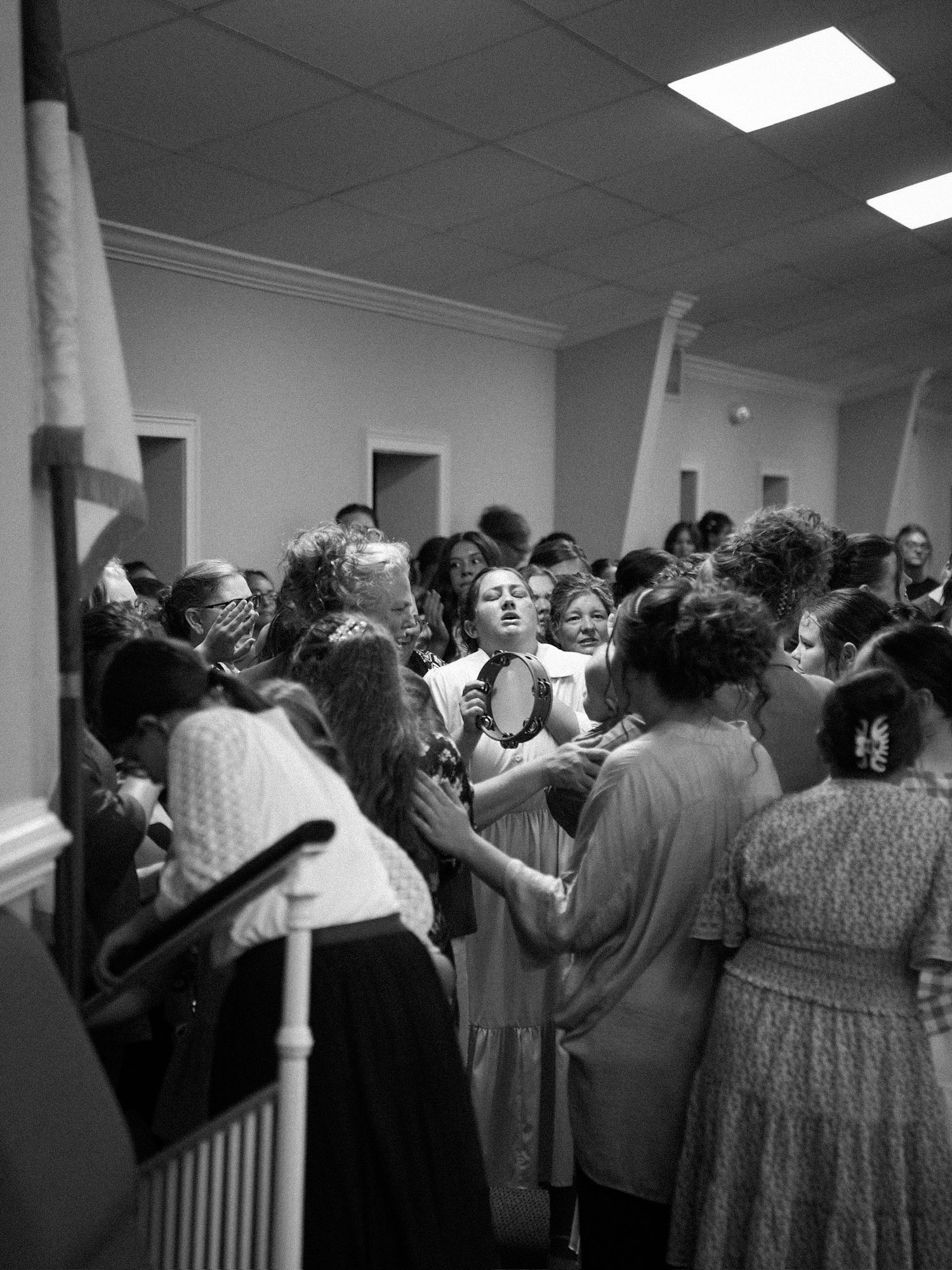 Black and white photo of women gathered in prayer circle during church service.
