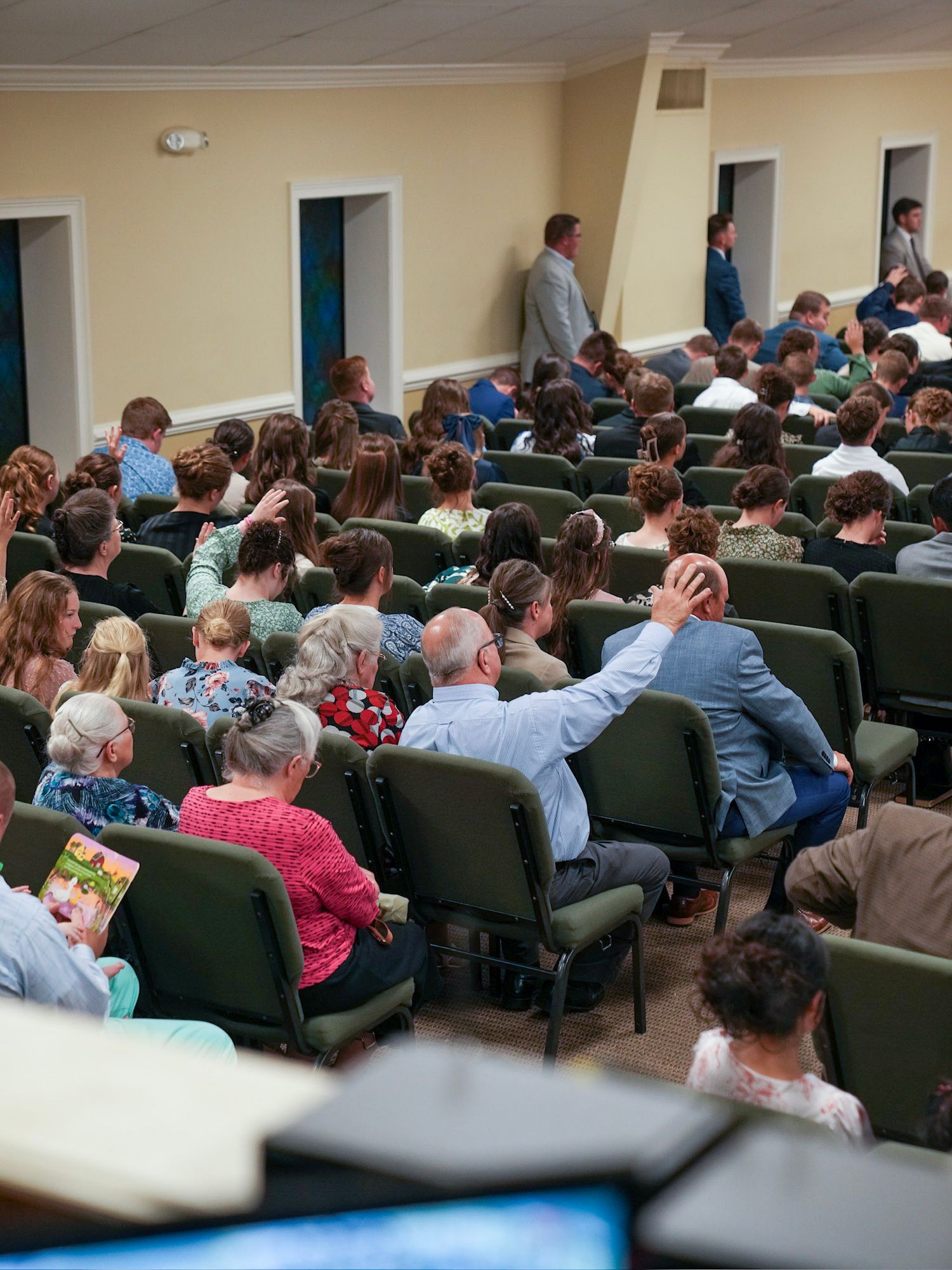 Congregation seated in green chairs during quiet moment of reflection in church.
