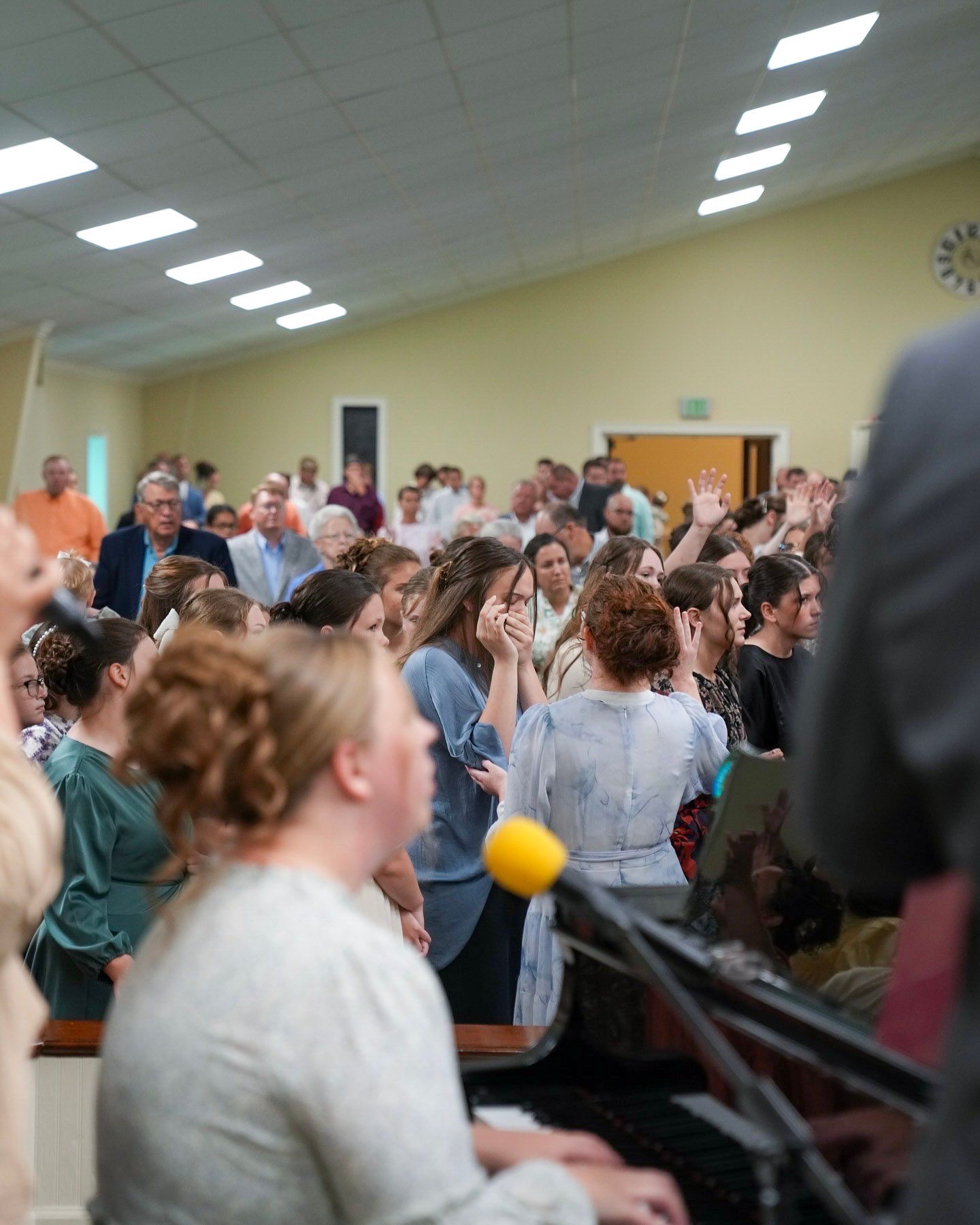 Large congregation worshipping with raised hands during emotional church revival meeting.