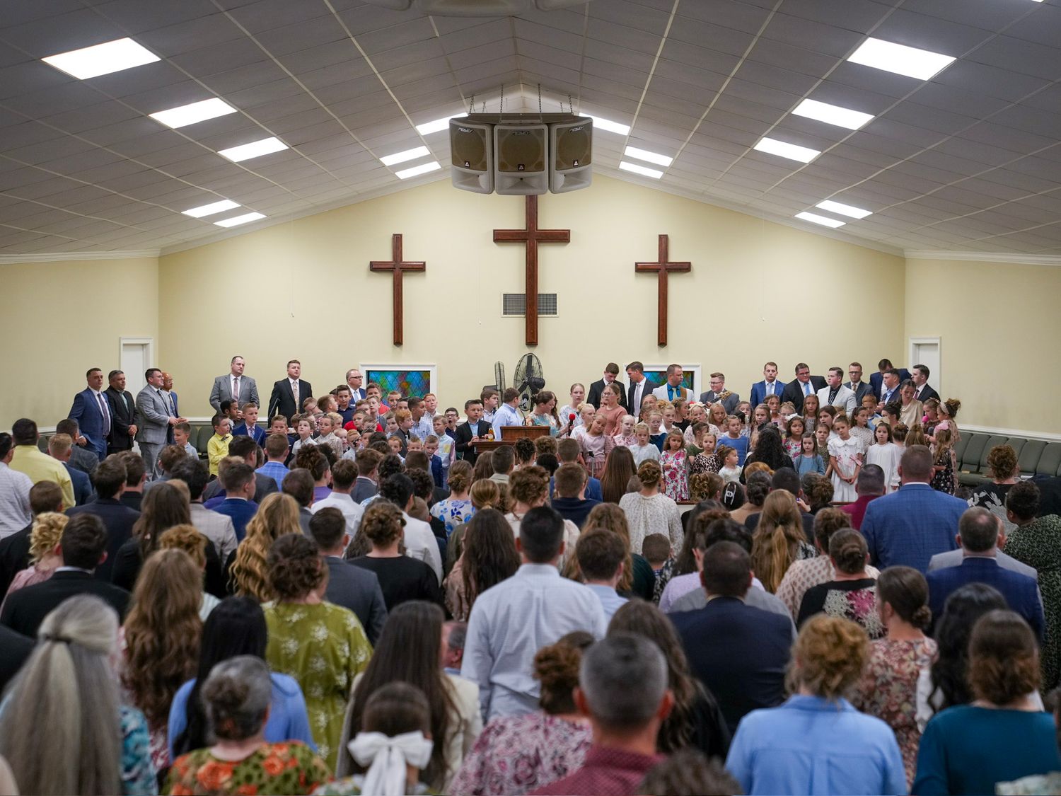 Large congregation gathered in church with three wooden crosses during a religious service.