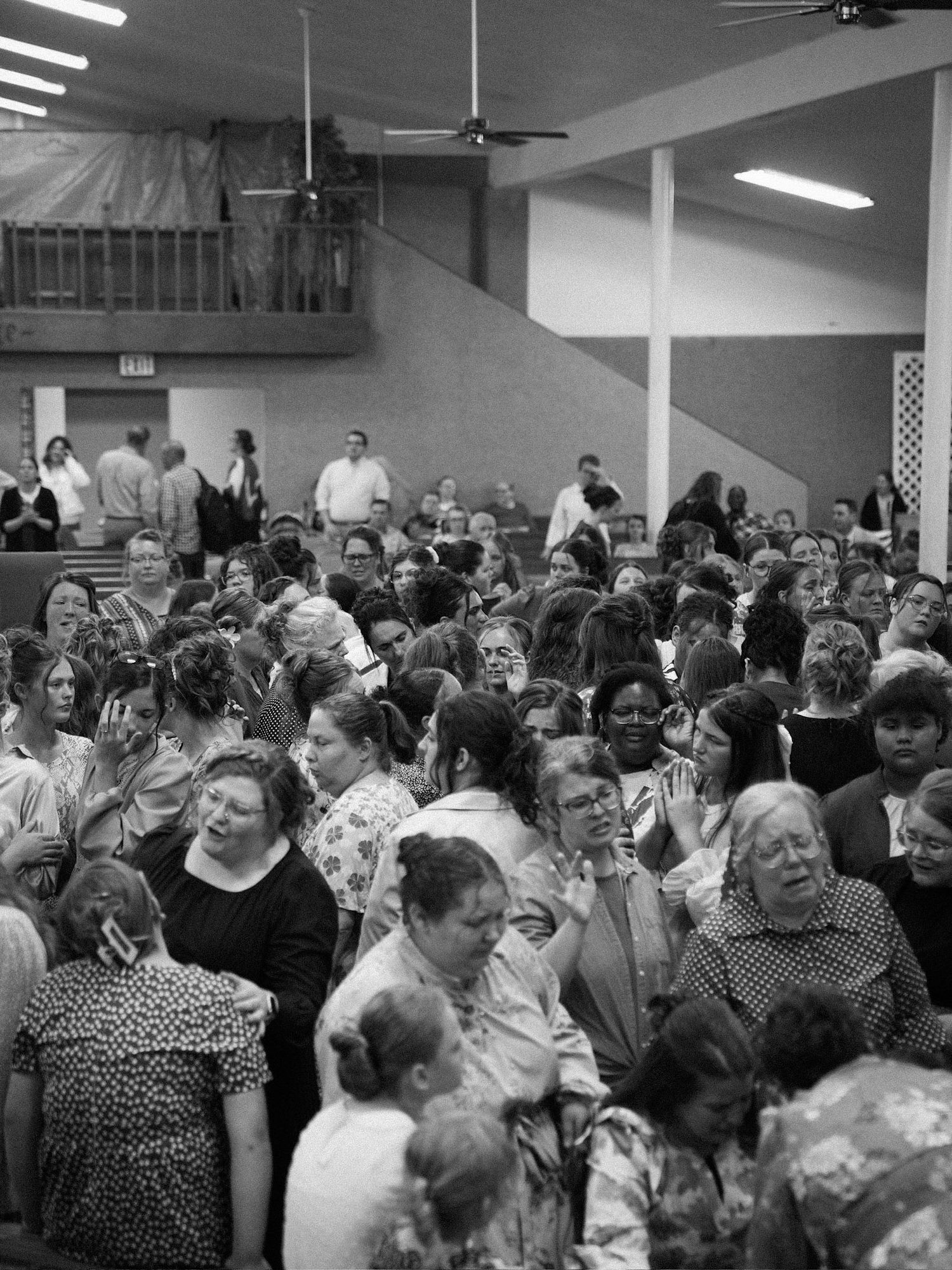 Black and white photo of a large congregation worshipping together in a packed church hall.