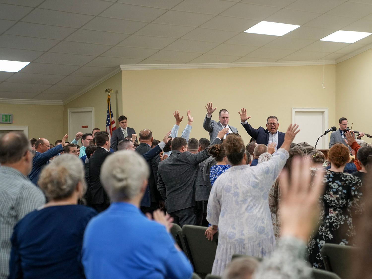 Congregation raising hands in worship during an emotional church revival service.