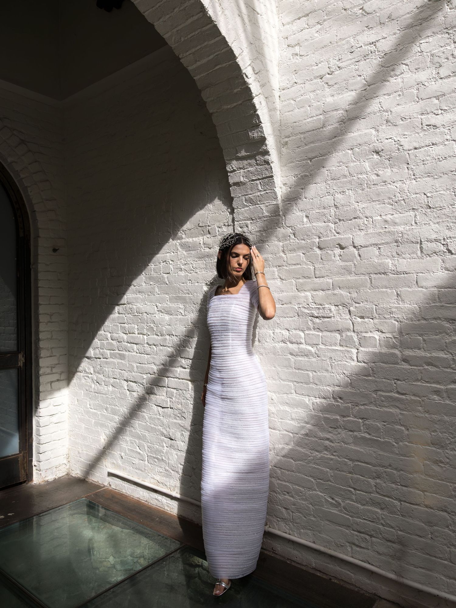 Bride in fitted white gown standing against white brick arch wall Foundry, Long Island City.