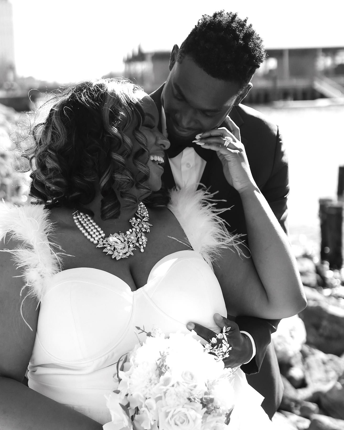 Black and white wedding photo of bride and groom sharing an intimate moment, bride wearing strapless gown and floral necklace.