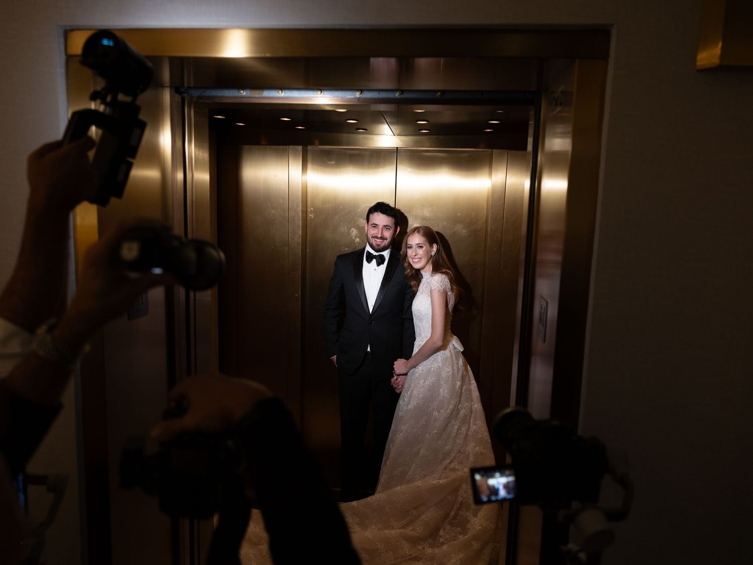 Bride and groom photographed in gold elevator doors at wedding reception in New Jersey