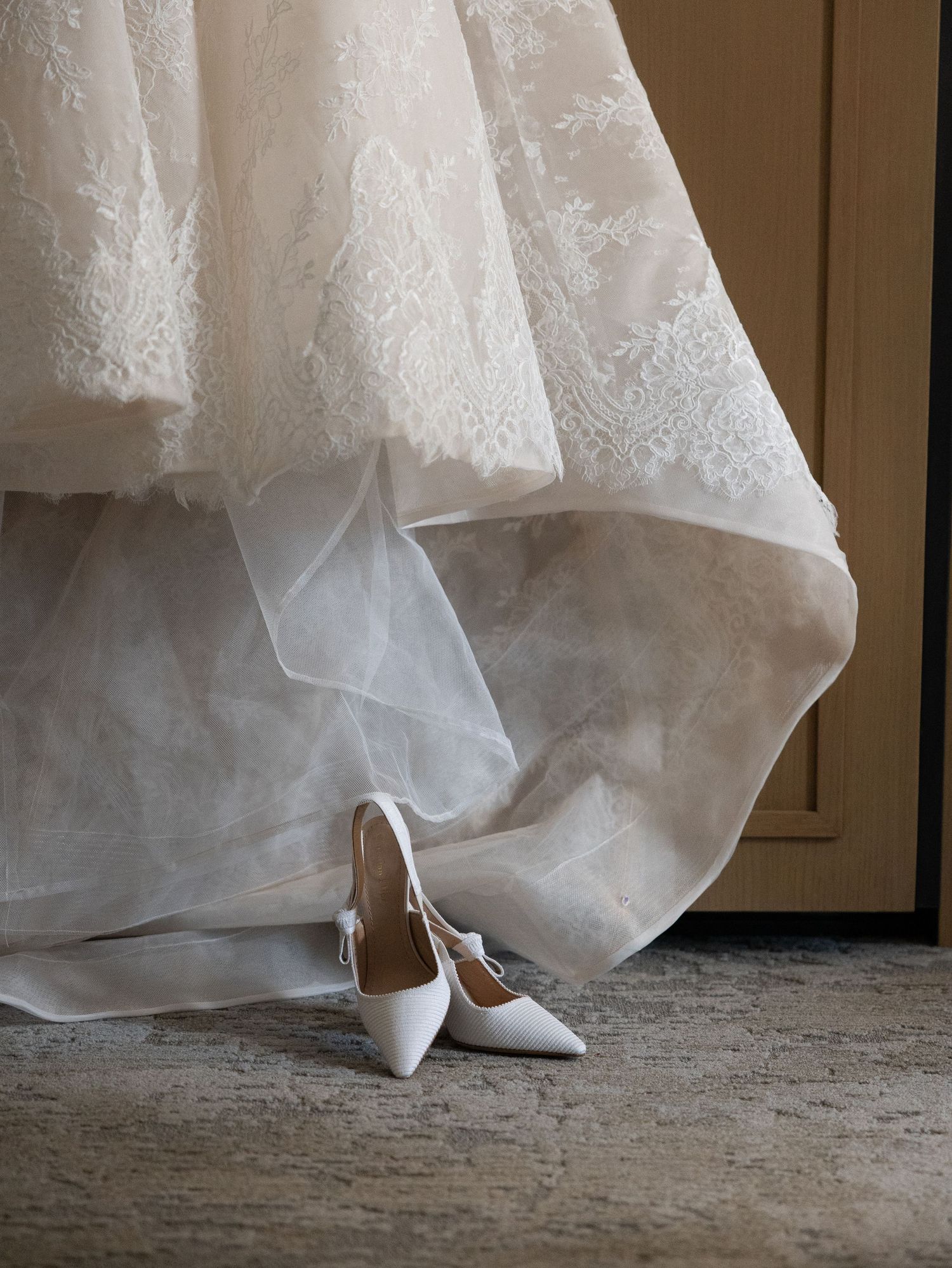 Elegant lace wedding gown train pooling on floor beside white pointed-toe heels in New Jersey