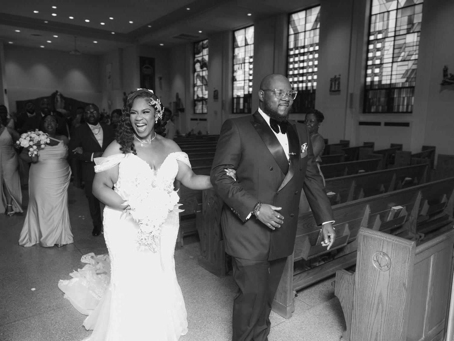Black and white photo of newlyweds walking down church aisle after ceremony in Queens, New York City.