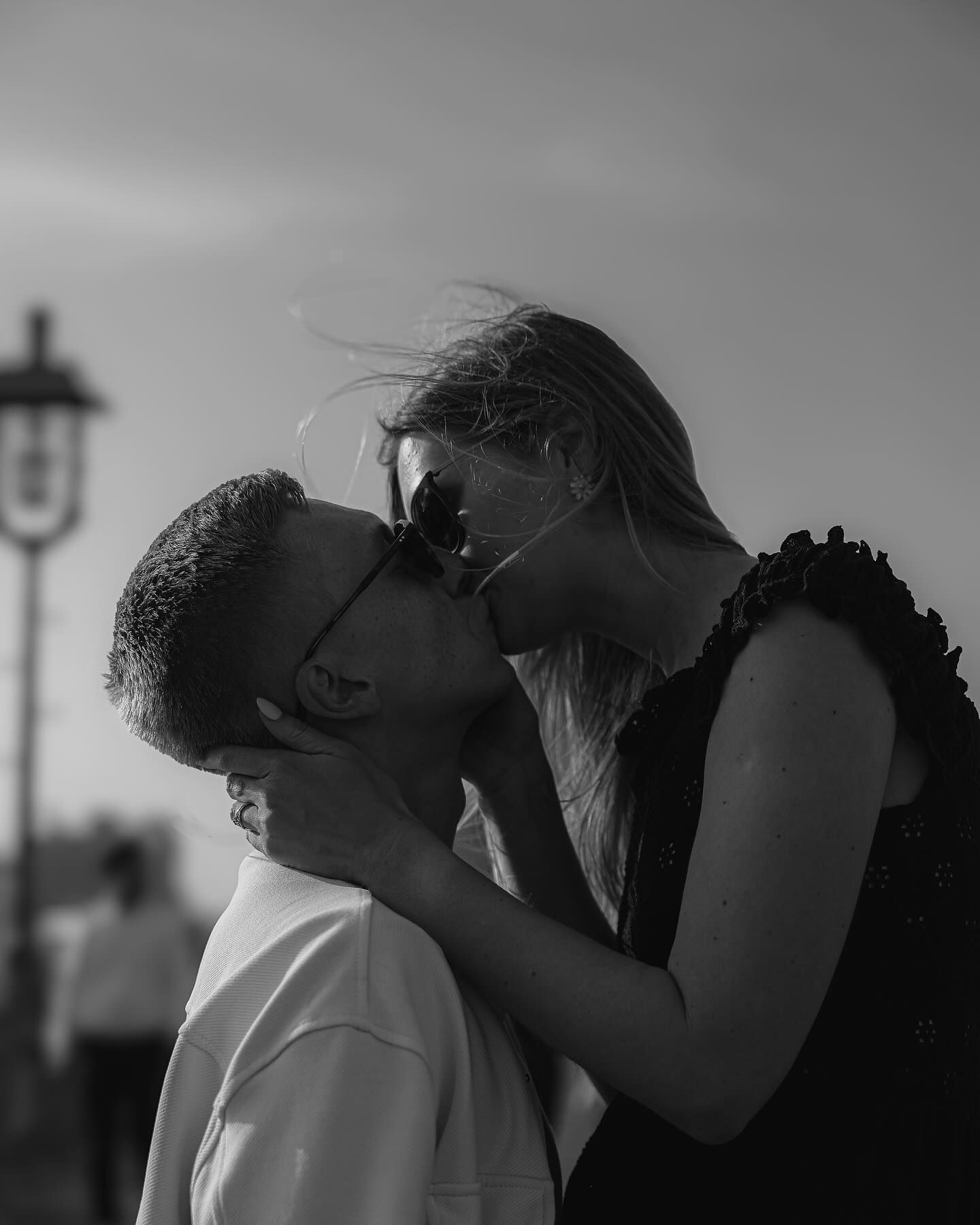 A romantic black and white photo of a couple about to kiss outdoors at dusk.