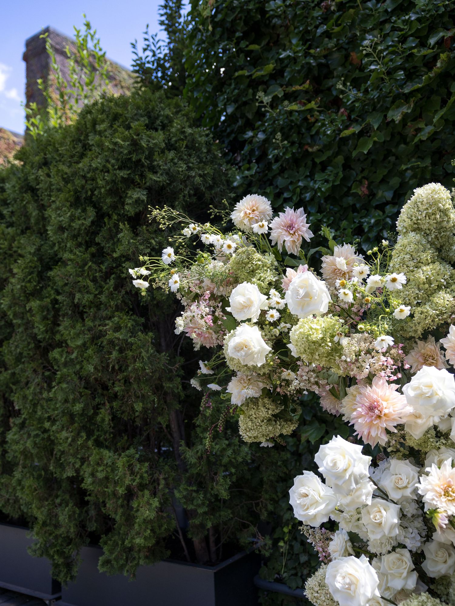 Lush white floral arrangement with roses and dahlias against green garden foliage Foundry, Long Island City.