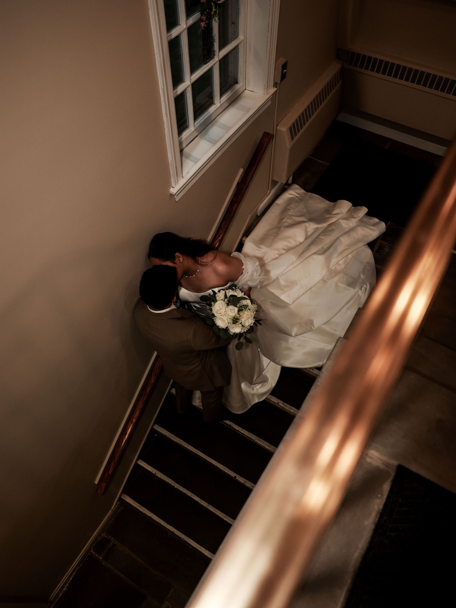 Aerial view of bride and groom kissing on staircase, bride holding white bouquet in a church in New Jersey .