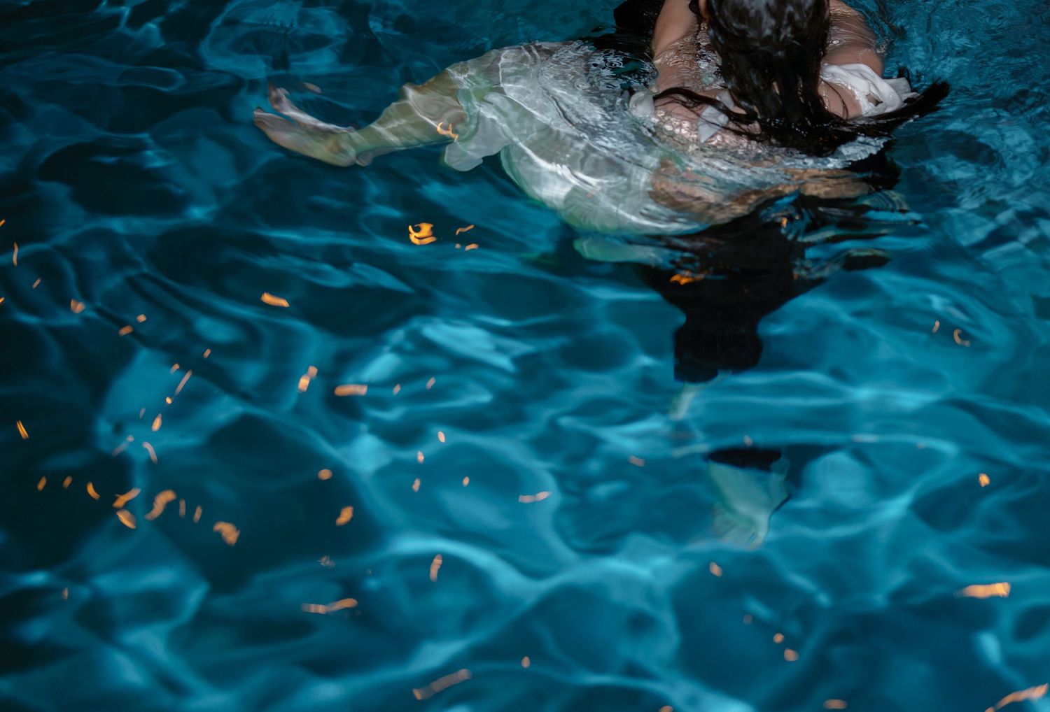 Underwater view of rippling blue pool water with sunlight creating shimmering patterns.
