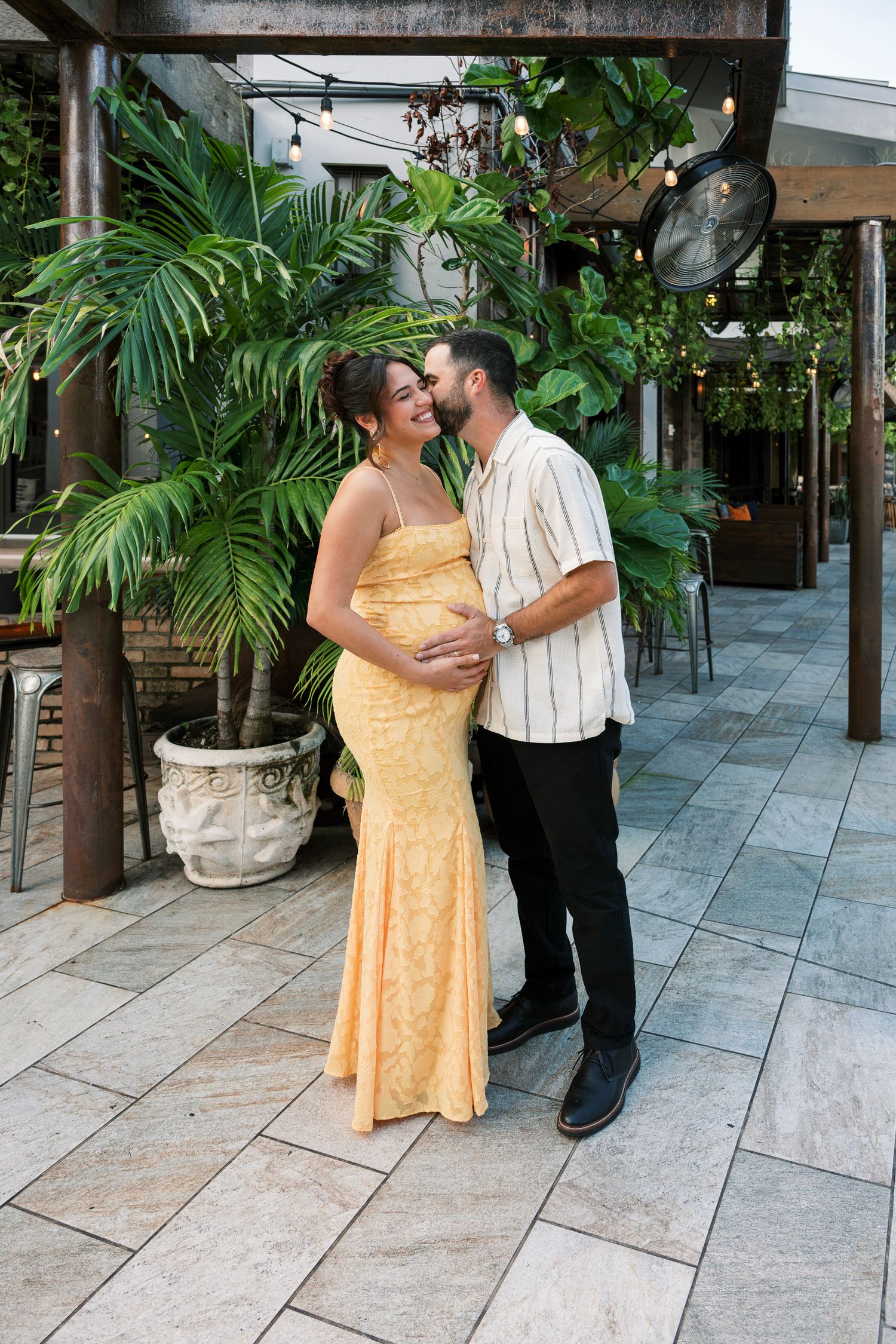 A couple shares a tender moment in a tropical garden setting.