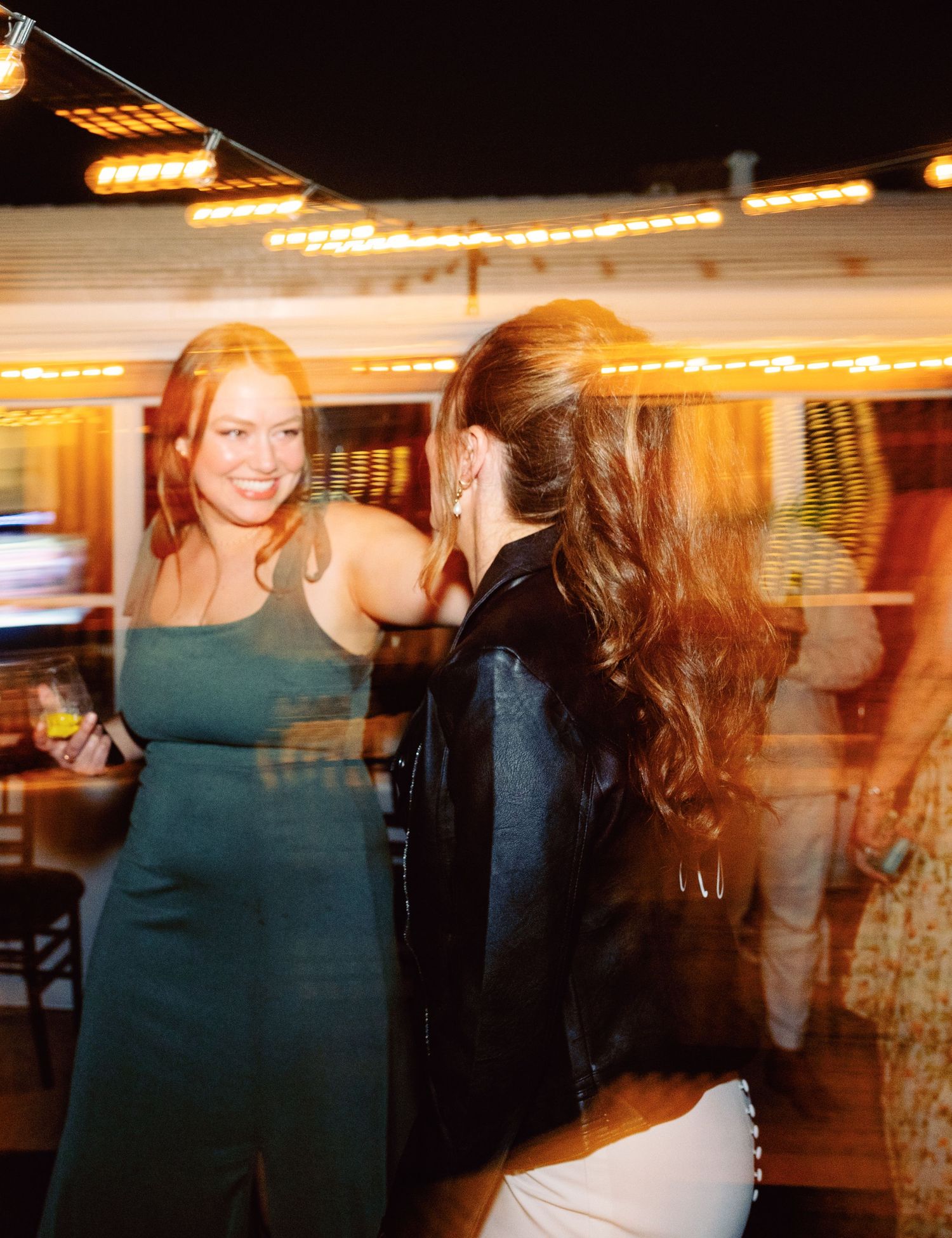 Motion blur sequence of wedding guests dancing under warm indoor lighting.