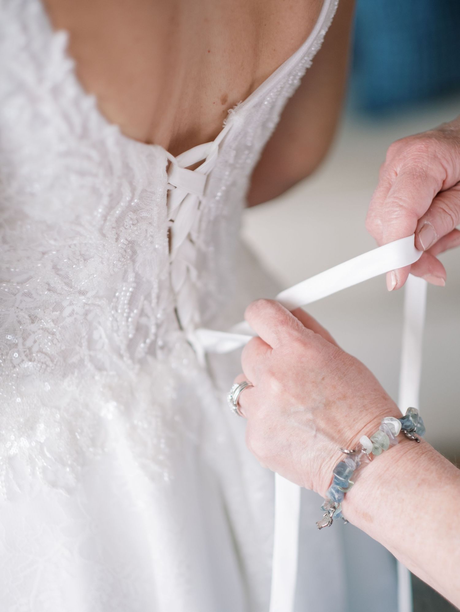 Close-up of hands adjusting white lace details on an elegant wedding dress.