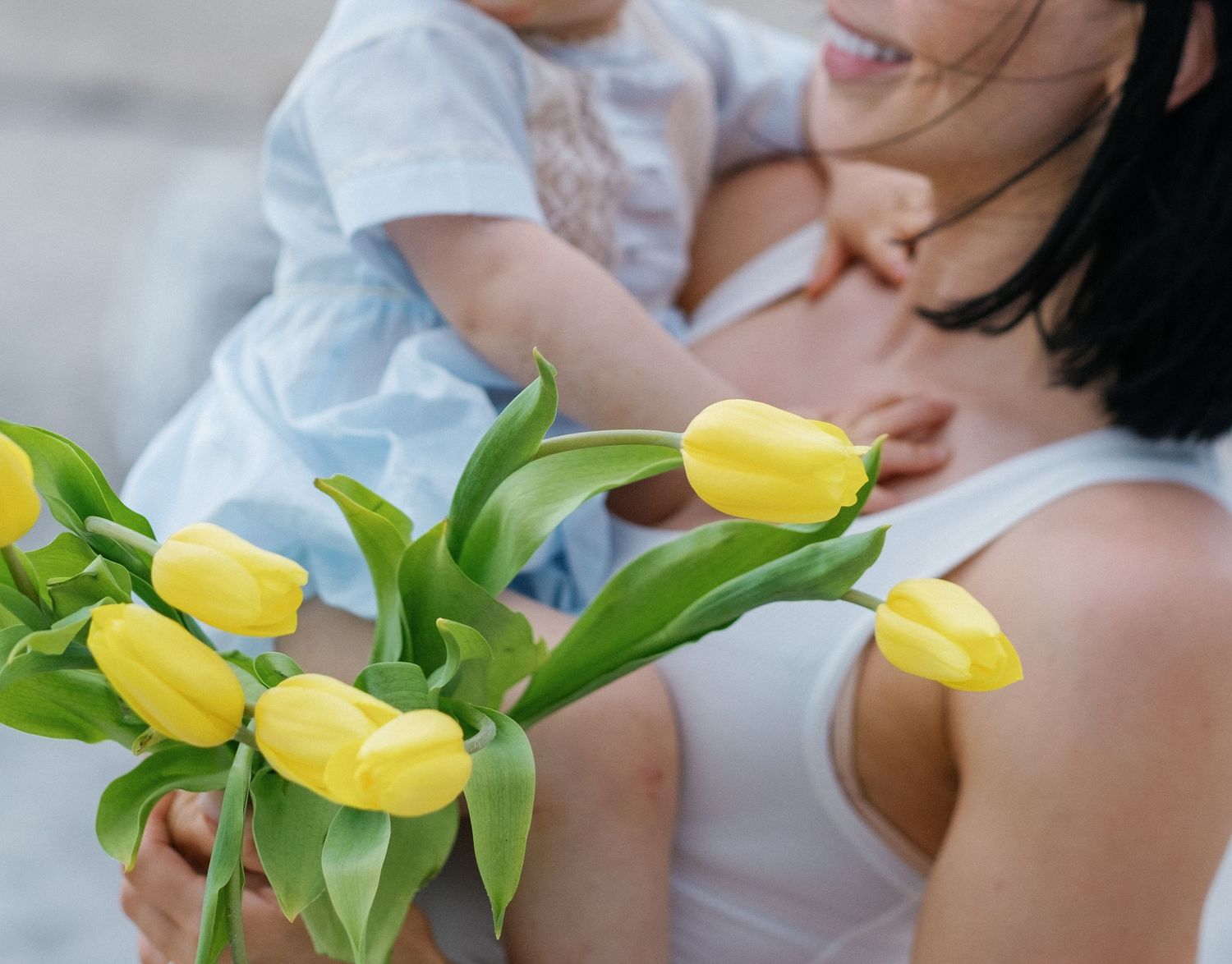 A close up shot of yellow tulips with green stems against a soft blurred background.