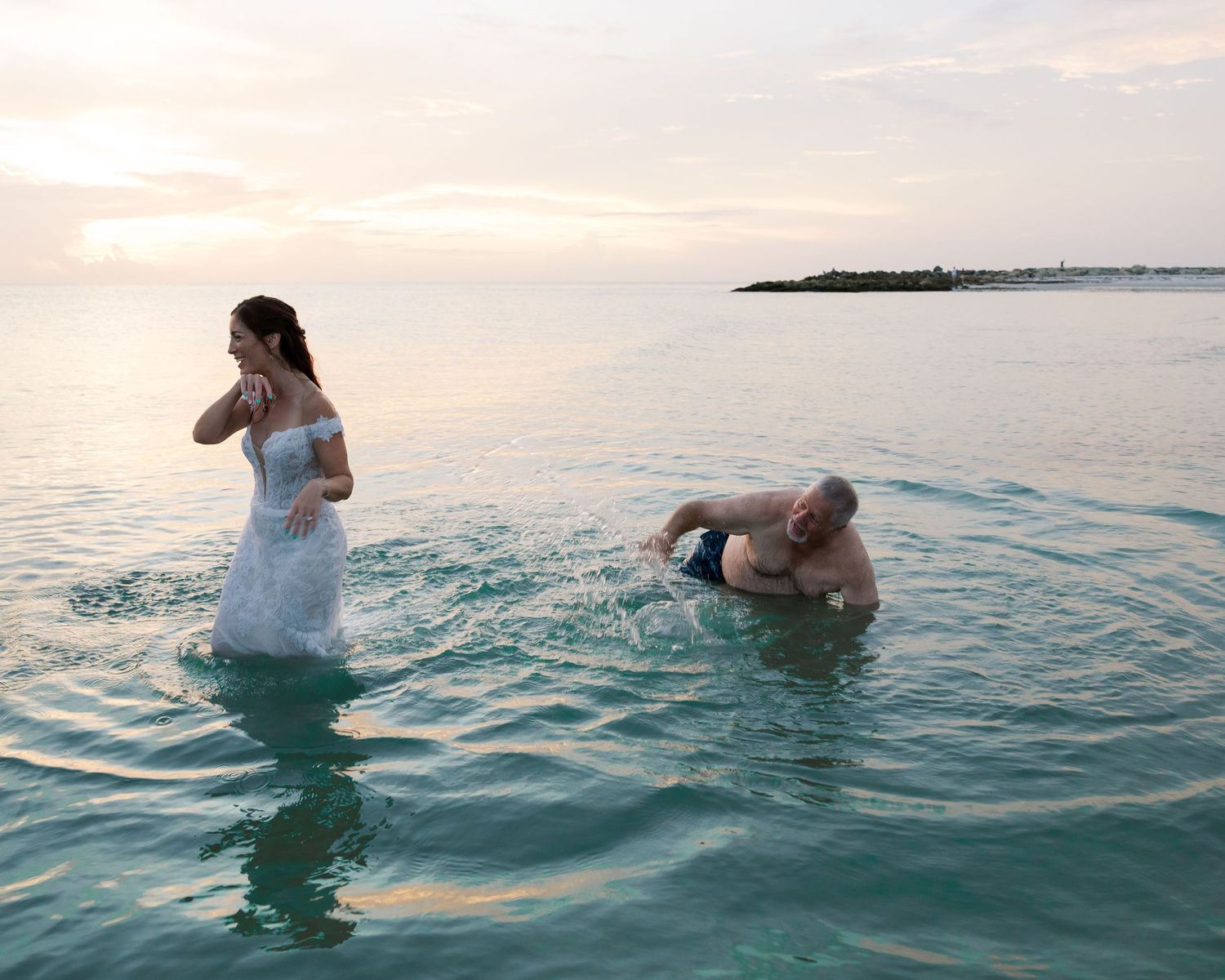 People enjoying a sunset swim in turquoise ocean waters near the shore.