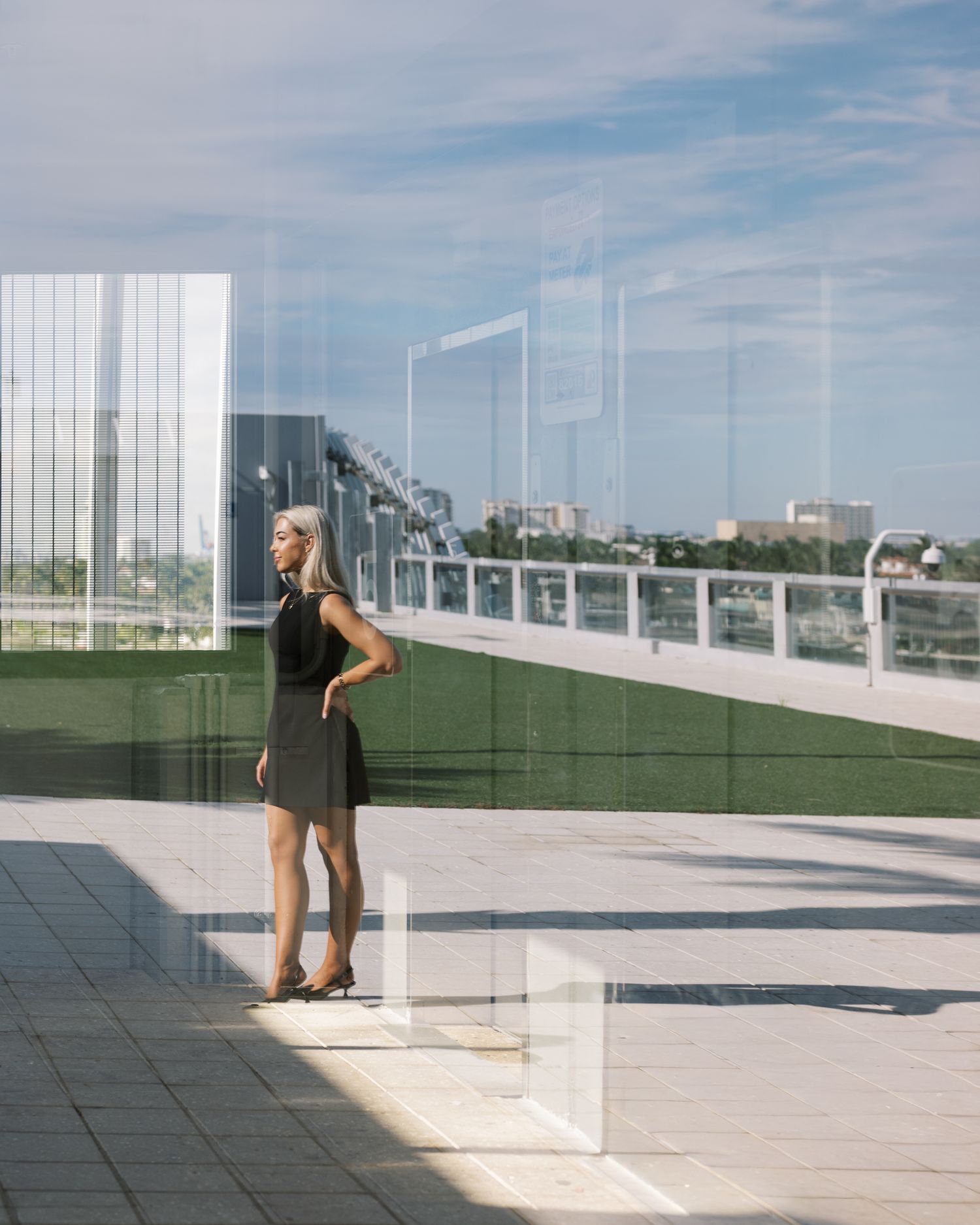 A sequence of photos showing a person in a dark outfit moving across a modern rooftop terrace with glass barriers and city views.