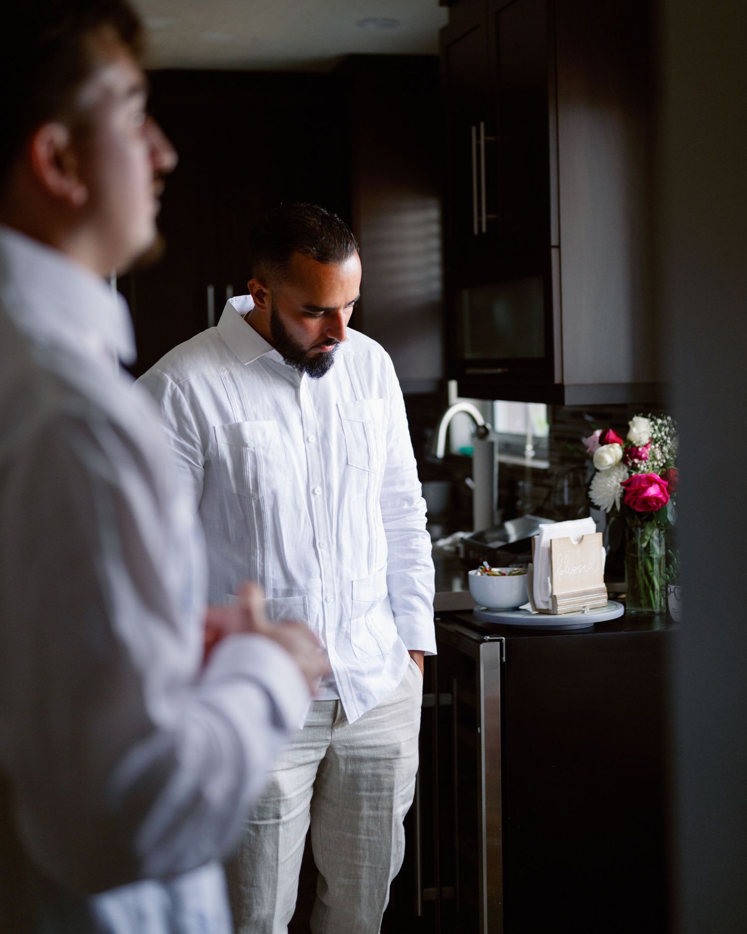 Kitchen staff in crisp white uniforms prepare for service in a dimly lit professional kitchen.