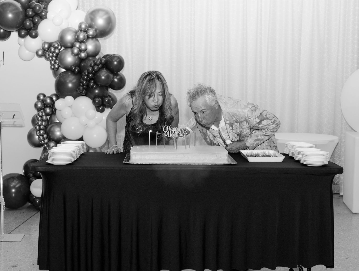 Black and white balloons decorate an elegant event setup with tables and buffet stations.
