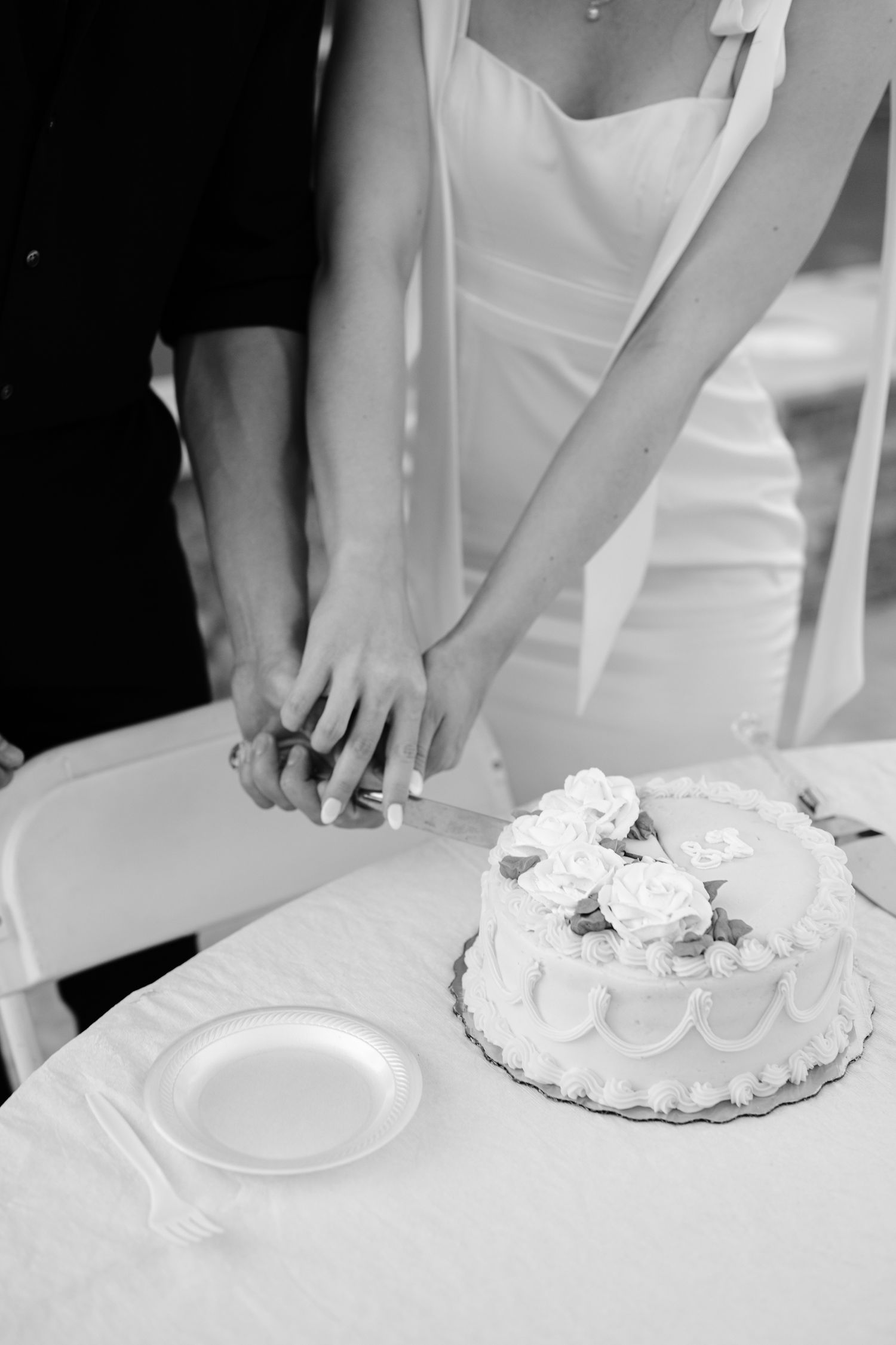 Black and white sequence of hands cutting and serving slices of a whipped cream decorated cake.