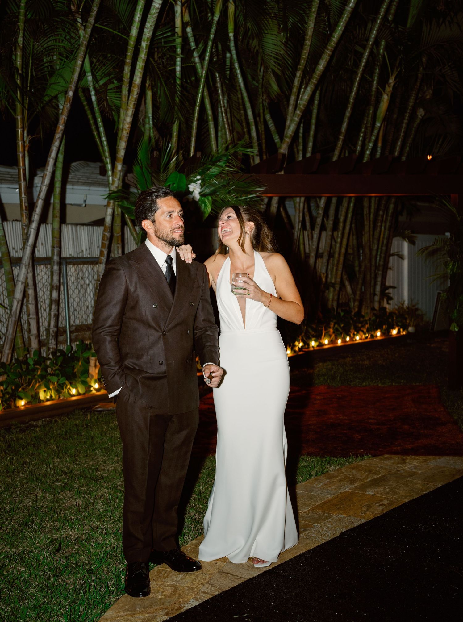 A couple enjoys an intimate evening moment under string lights and bamboo trees.