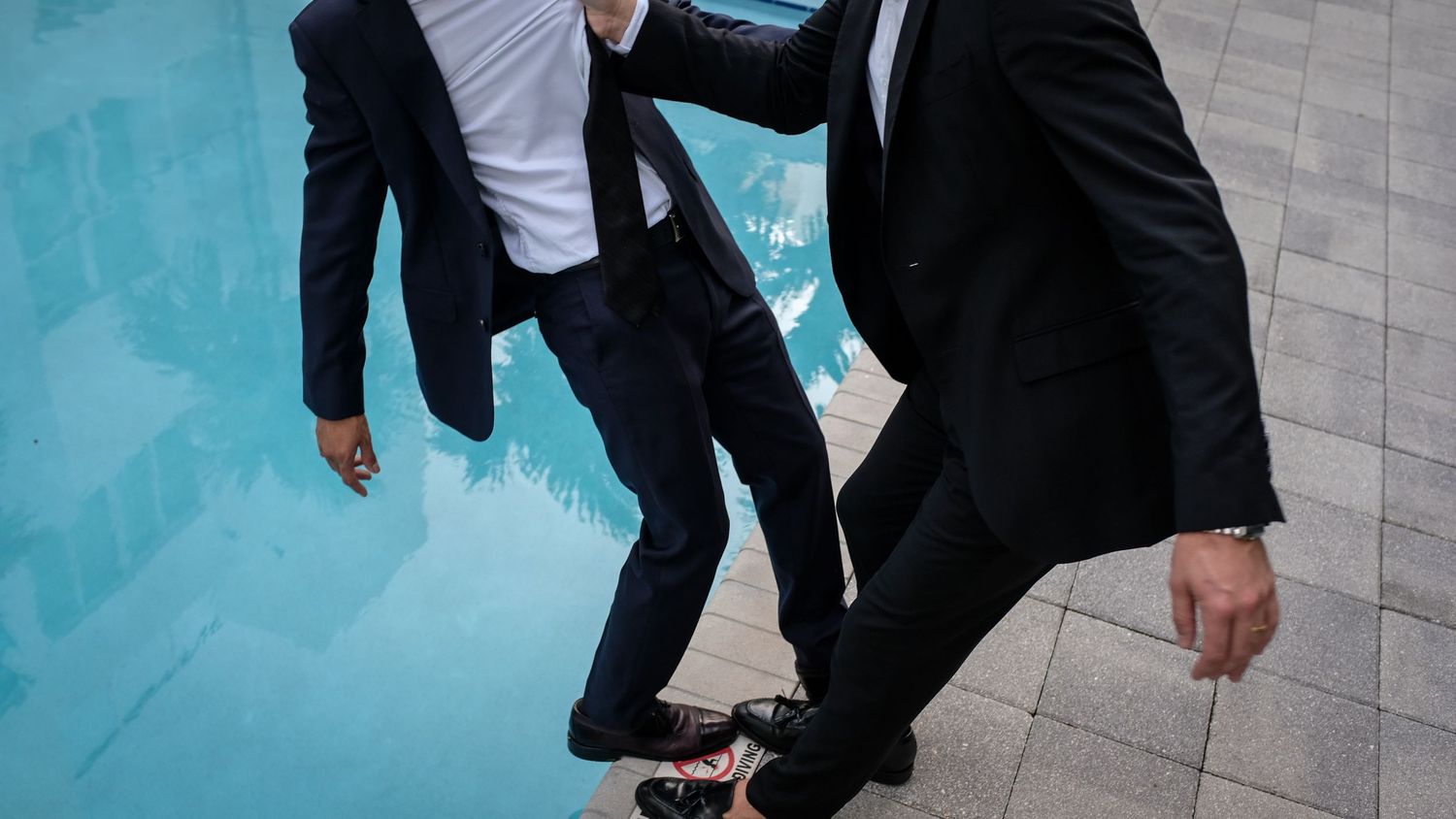 Person in business attire falls backwards on teal background in sequence of motion blur photographs.