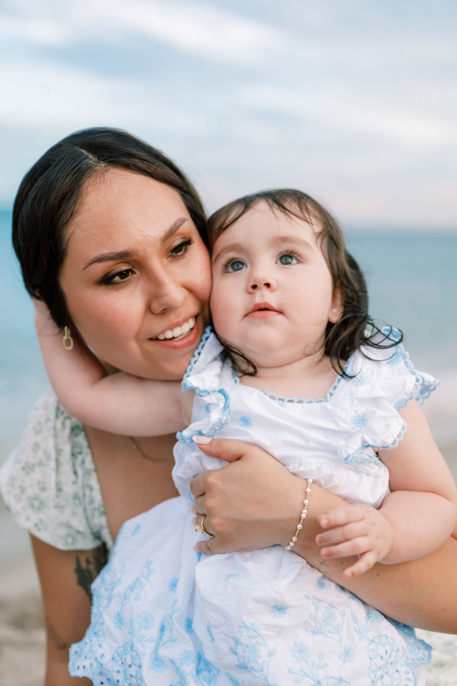 Series of tender moments between parent and child in matching blue and white outfits at the beach.