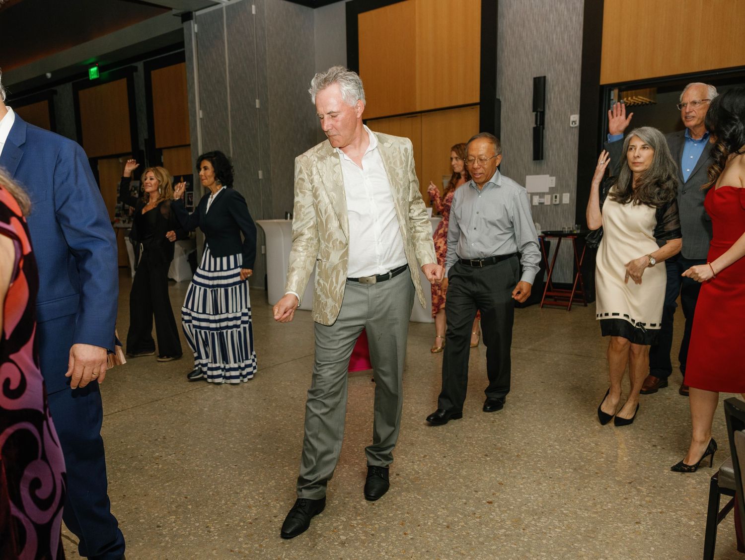 Guests mingling and dancing at a social gathering in a spacious venue with modern decor.
