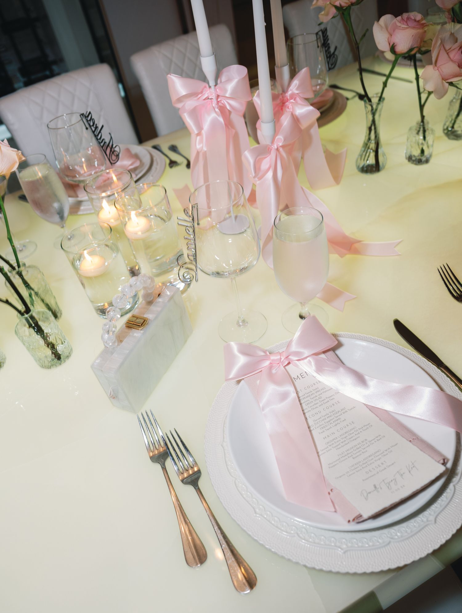 Elegant table settings with white plates, pink napkins, and candlelight create a romantic atmosphere for a special occasion.