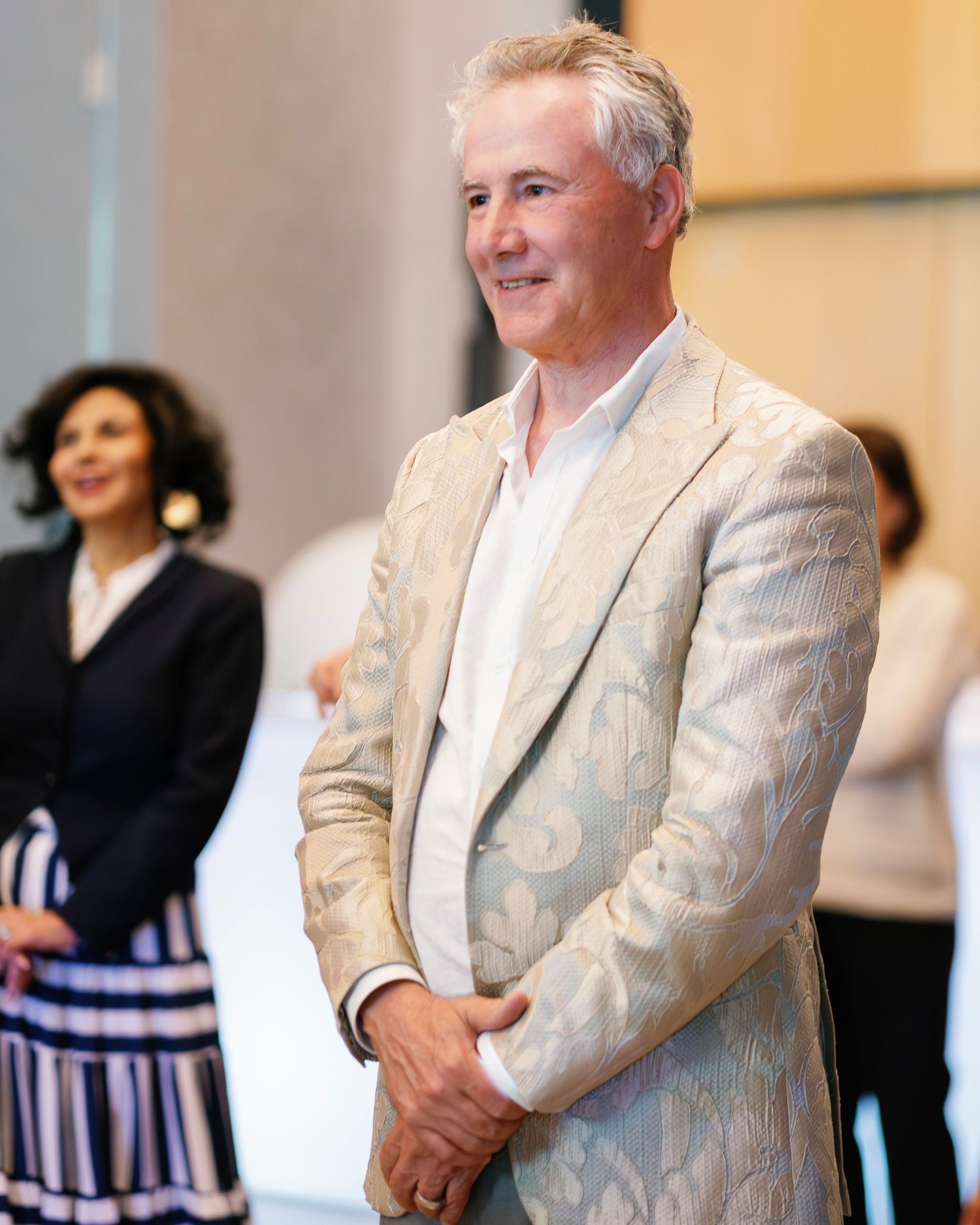 Multiple images of someone wearing a light colored suit jacket standing in an indoor setting.