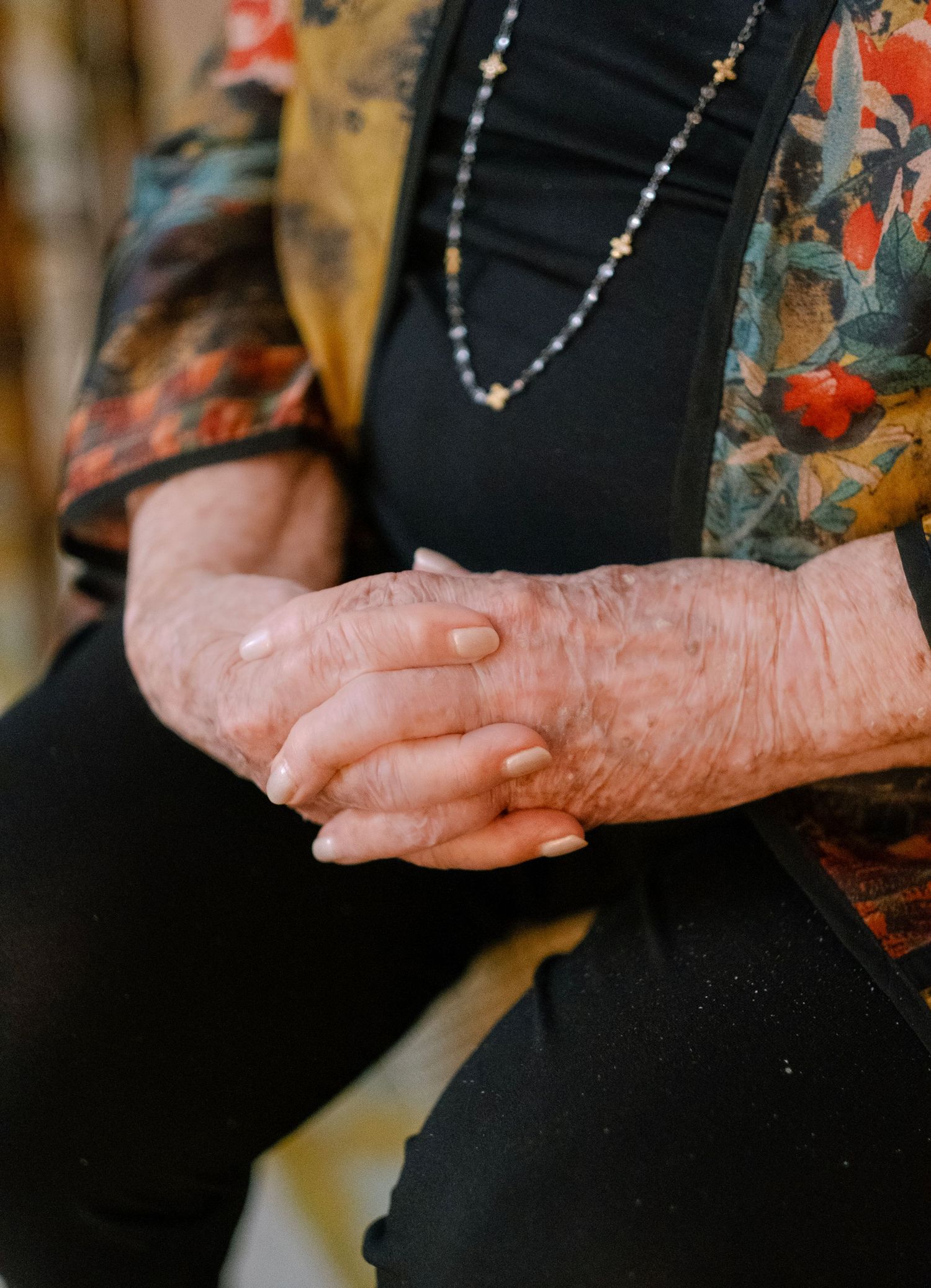 Close-up of weathered hands resting together against a black garment.
