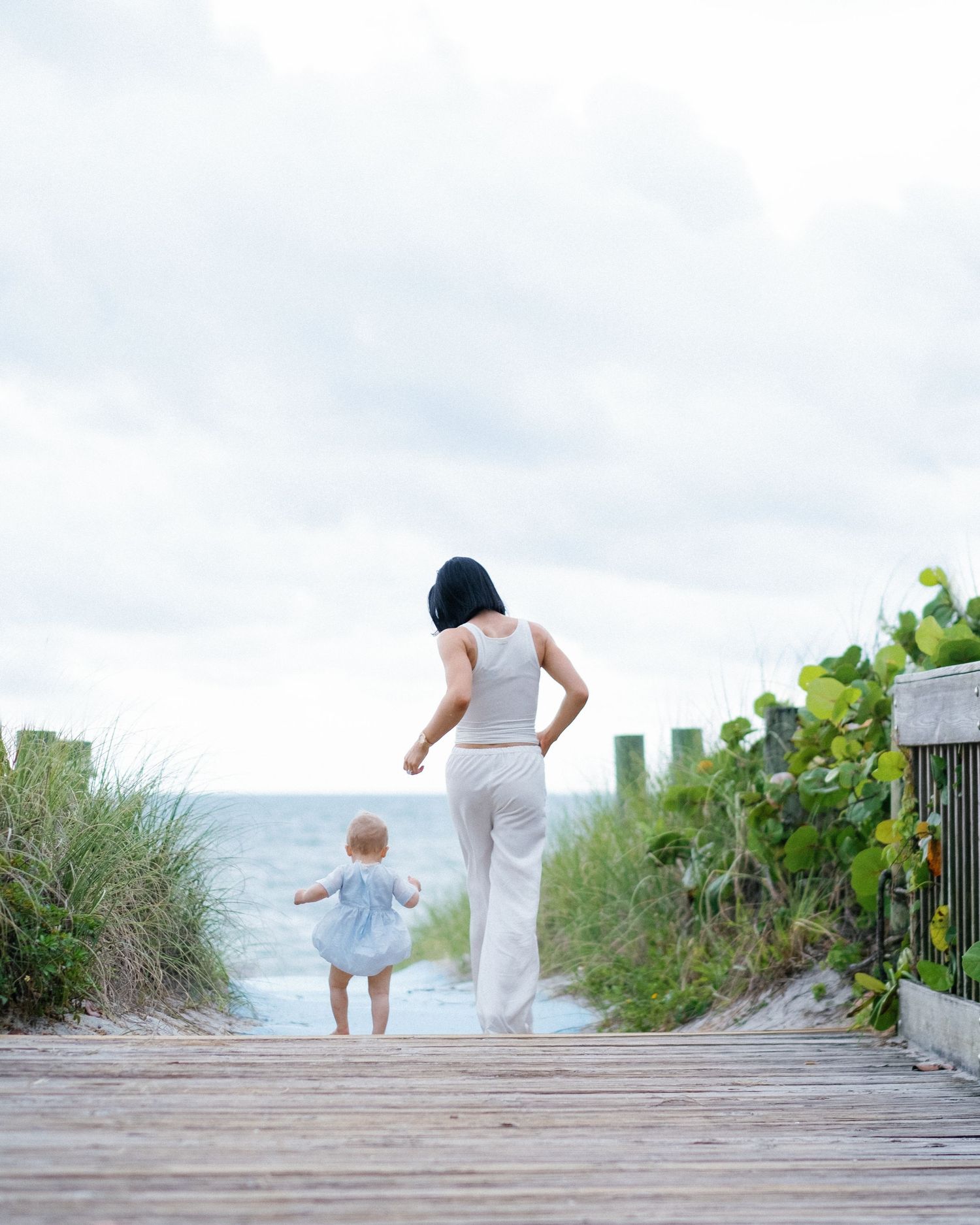 A sequence of images showing a parent and child walking down a wooden boardwalk towards the beach.