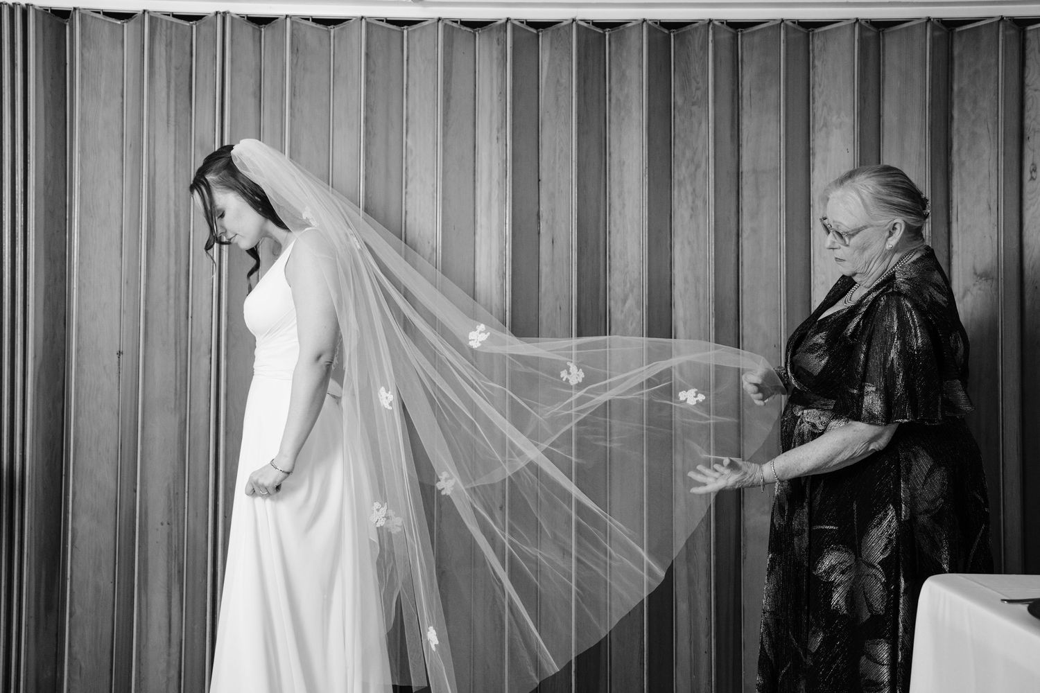 Black and white photo showing wedding veils hanging in a row against a striped wall.