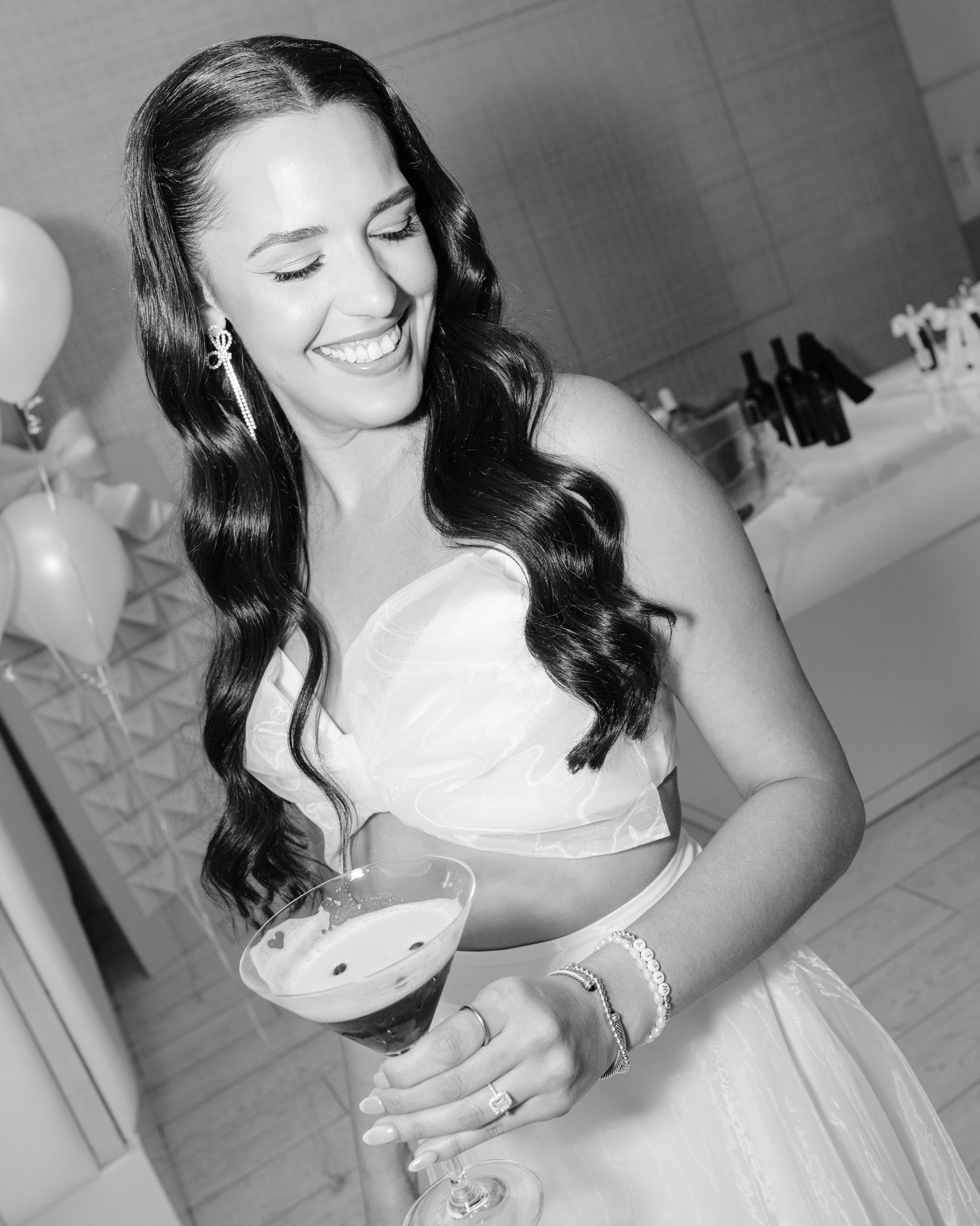 Bride holding a glass and smiling during a wedding celebration in black and white photography.
