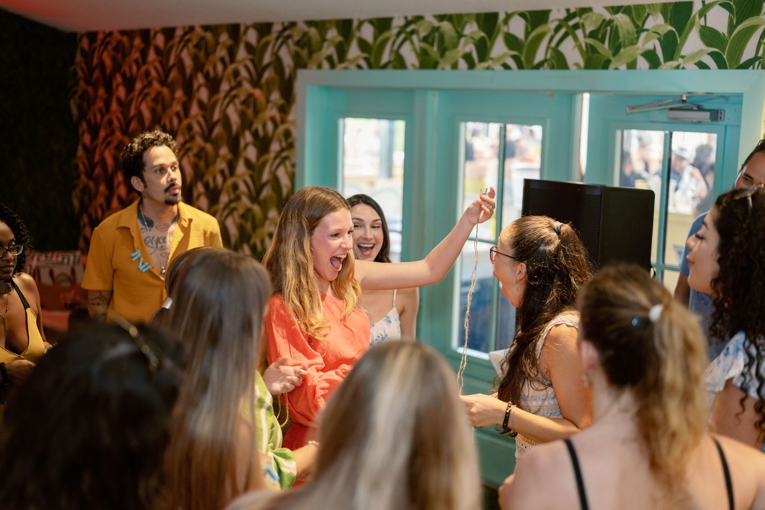 Crowd of people gathered in a room with turquoise walls for a social event.