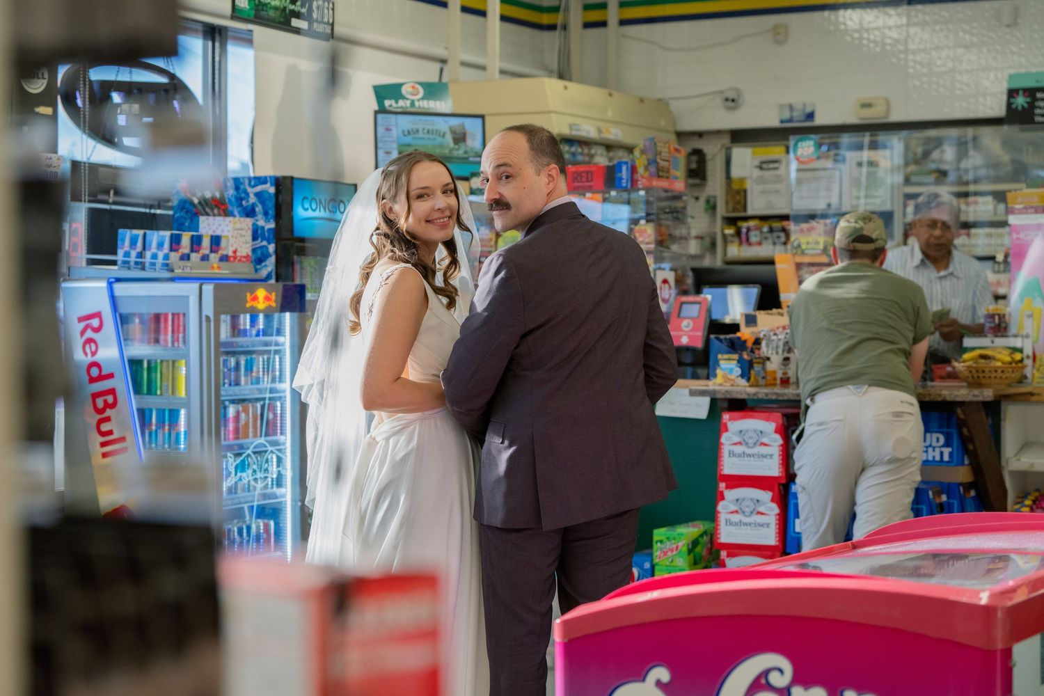 A couple stands at a pharmacy counter with shelves of products visible in the background.